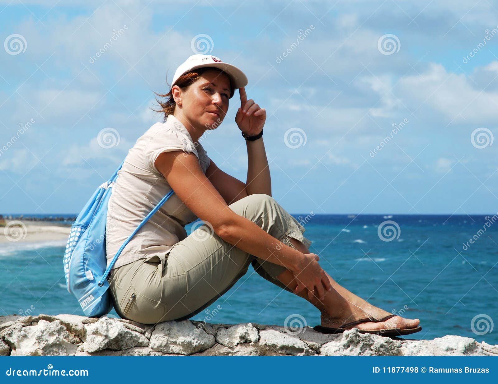 Sedendosi su una parete. La ragazza che si siede su una parete di pietra e che gode della vista della spiaggia dell'isola di paradiso (Bahamas).