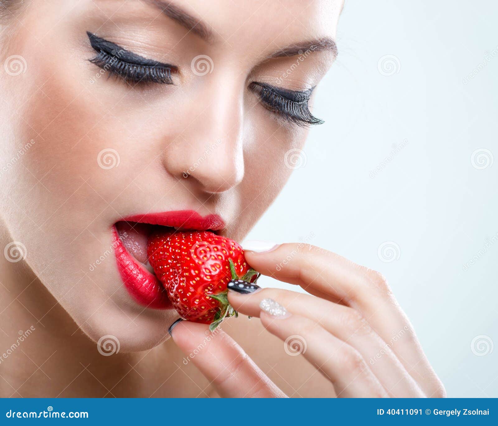 seduction - beautiful woman when closed eyes, take a bite of the strawberry
