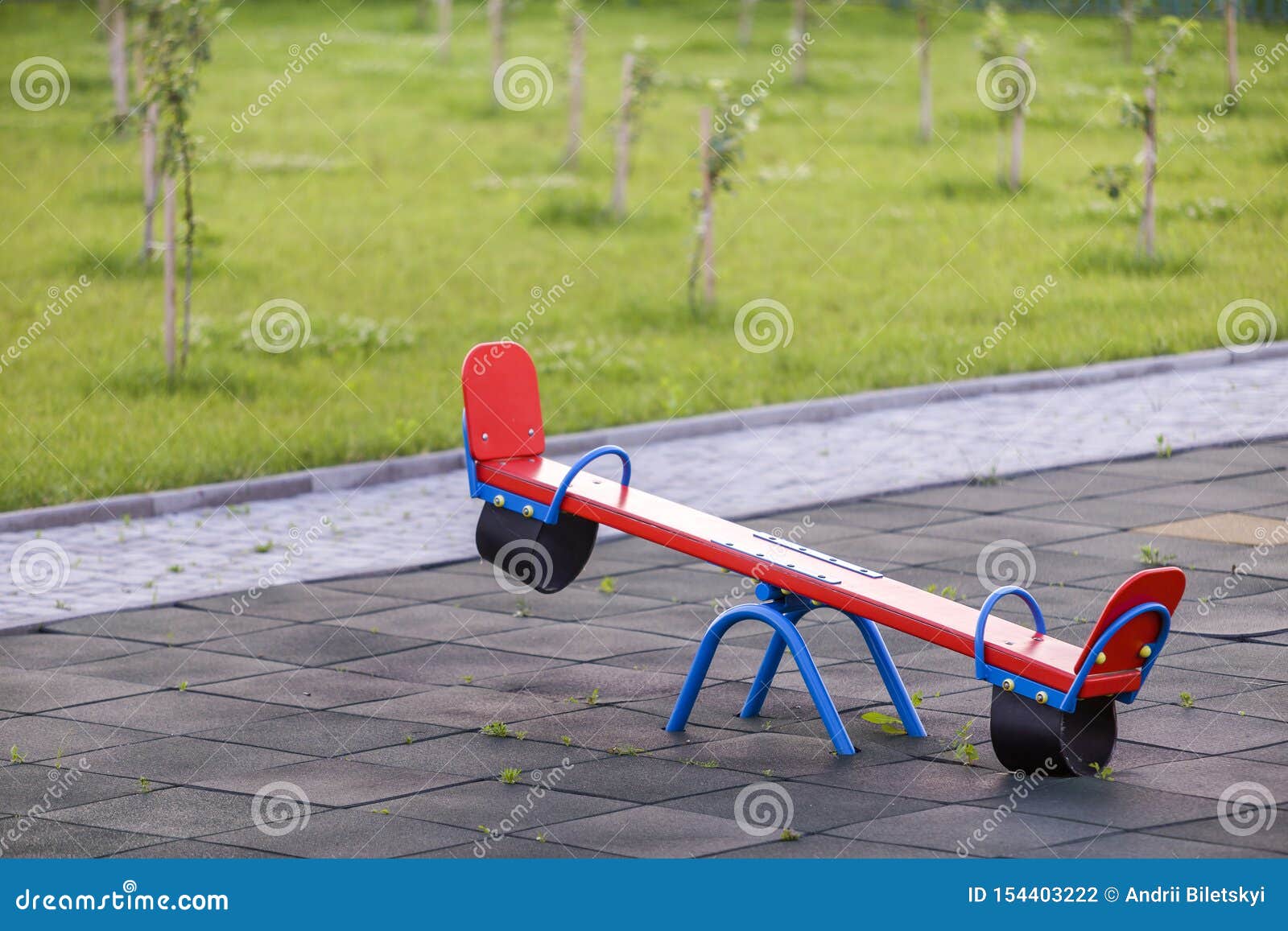 seesaw swing in big yard with soft rubber flooring on sunny summer day