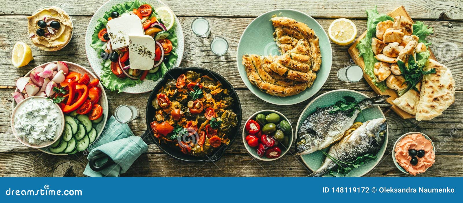 selection of traditional greek food - salad, meze, pie, fish, tzatziki, dolma on wood background