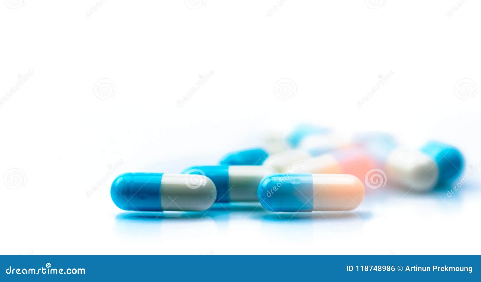 selective focus on blue and white capsules pill spread on white background with shadow. global healthcare concept. antibiotics