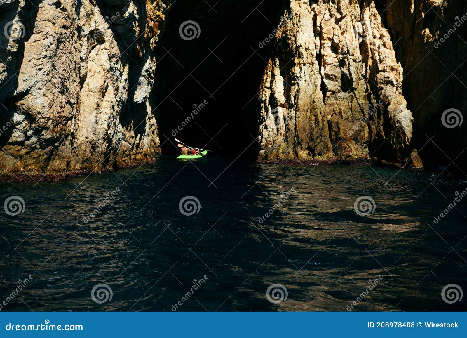 selective focus - father and son rowing in a canoe to enter a natural cave in the mediterranean sea