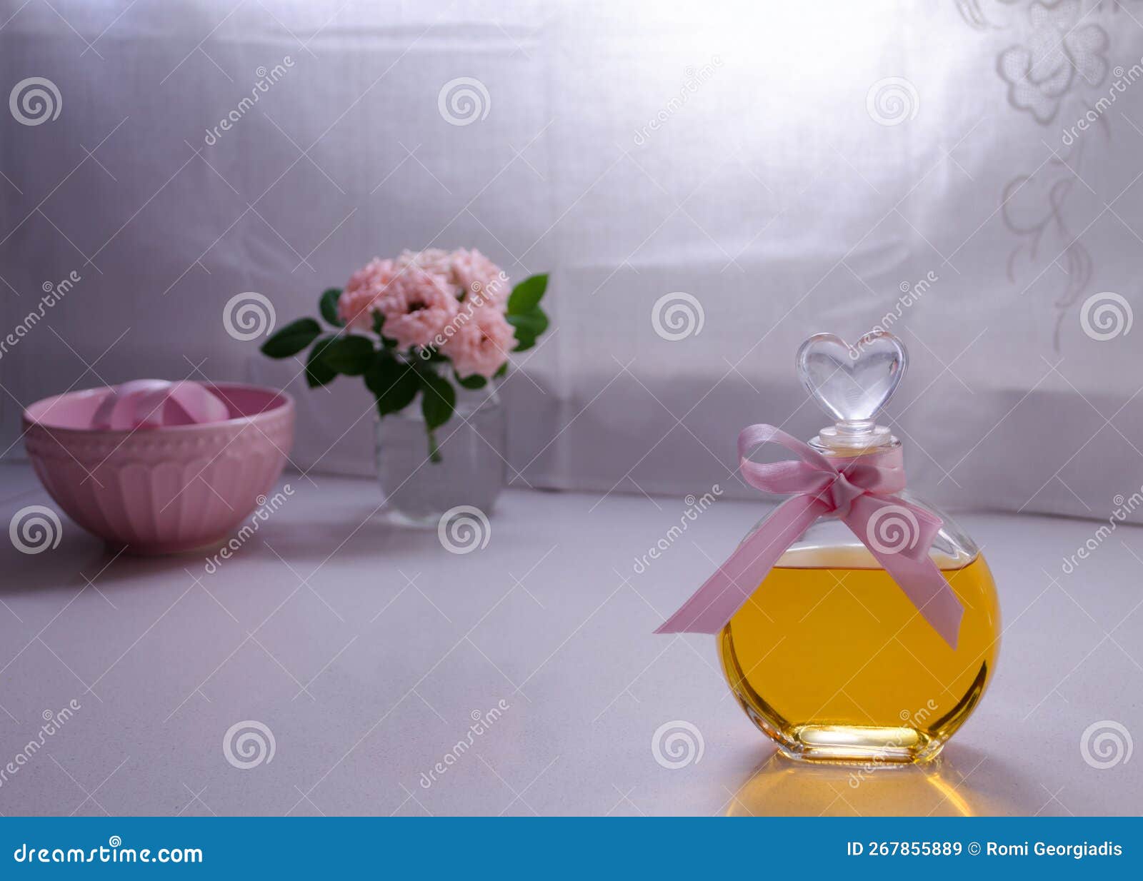 selective focus of fragance bottle, roses bouquet and pink bowl on background