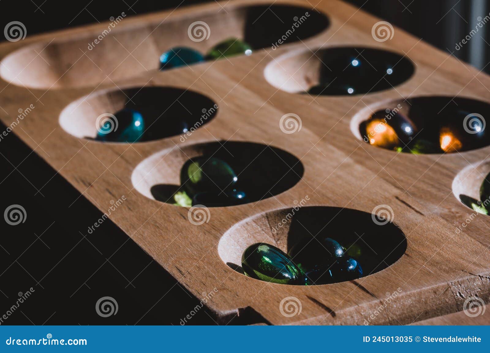 selective focus on glass beads on a wooden mancala board