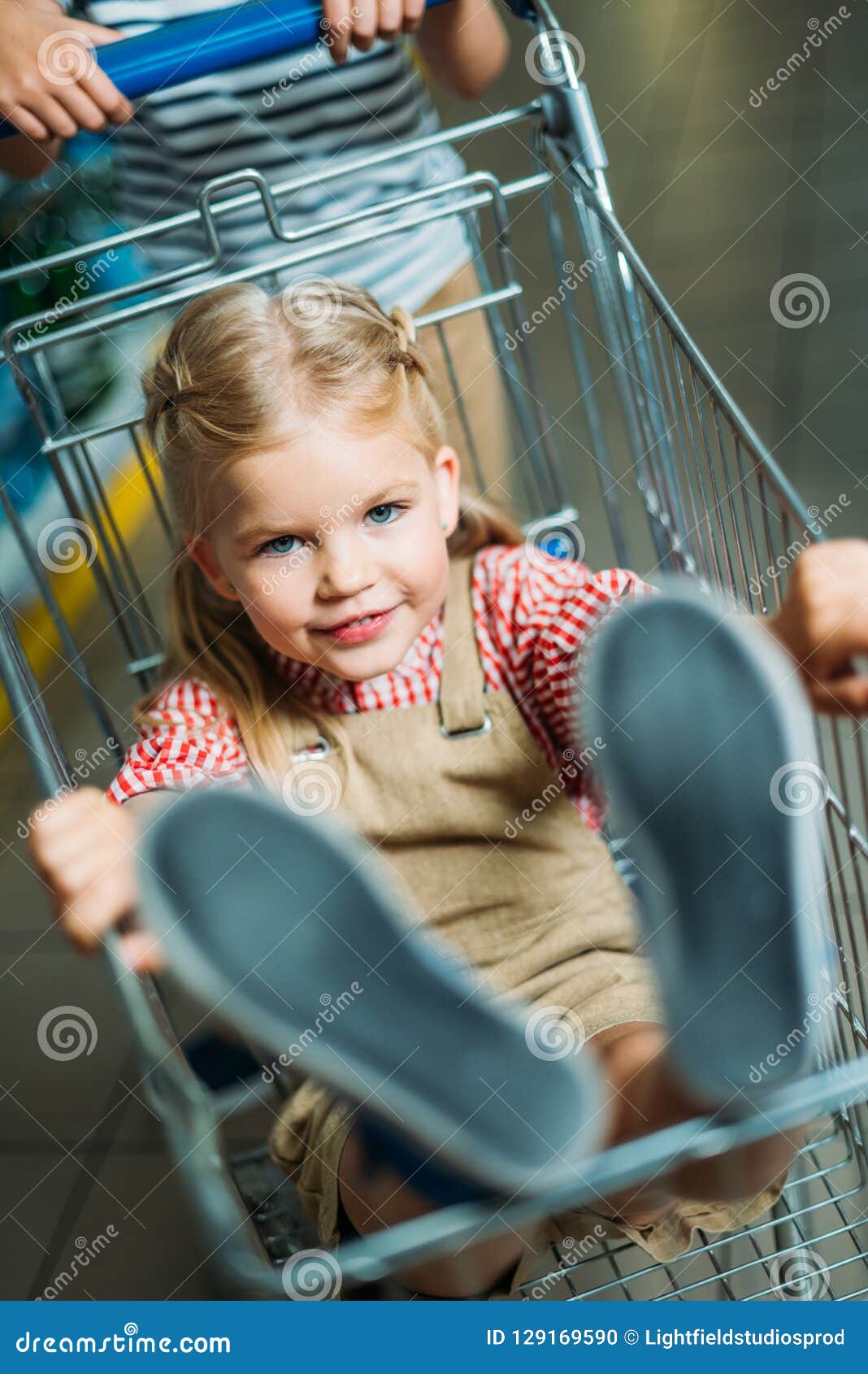 selective focus of little girl sitting in shopping cart