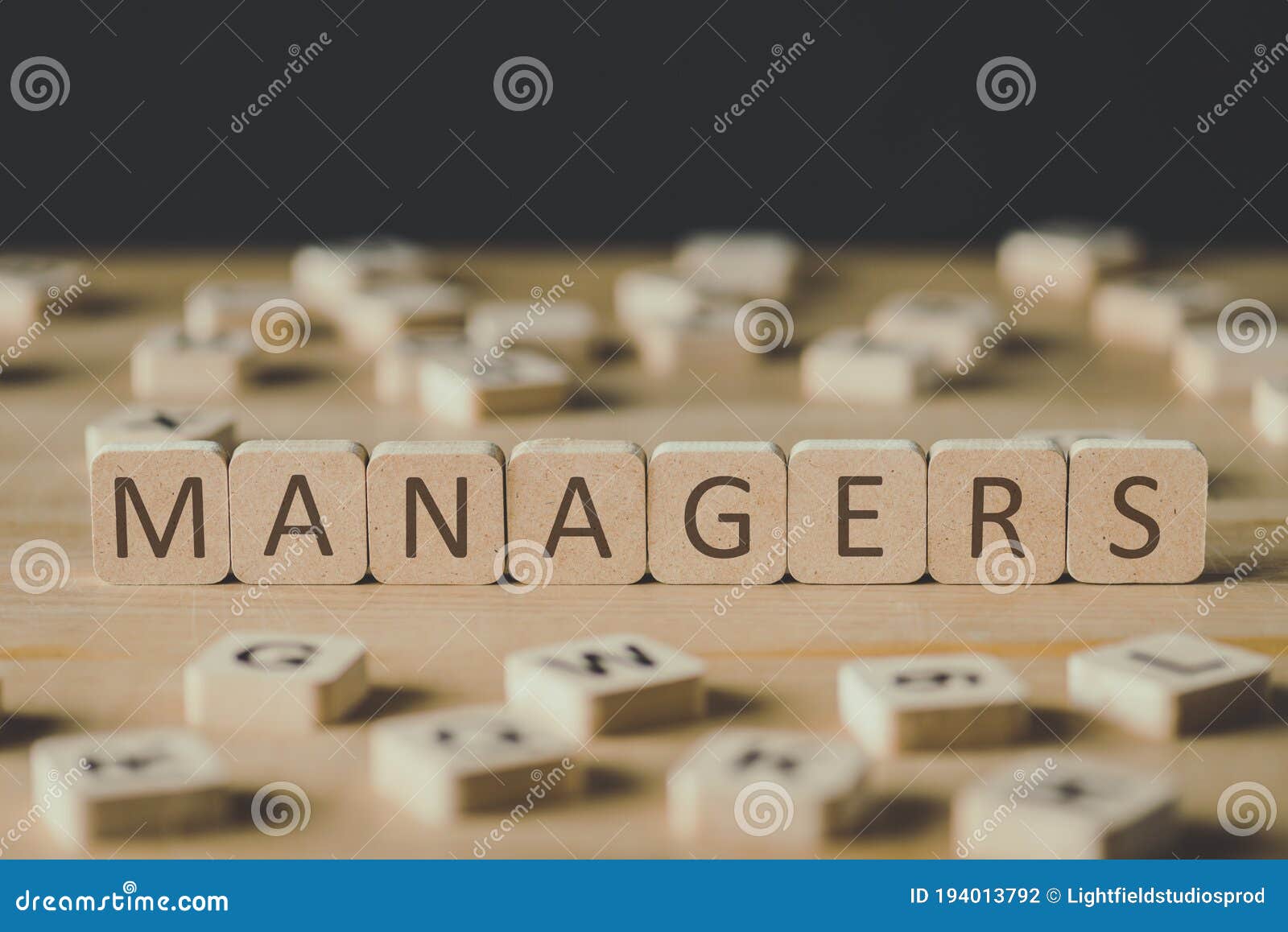 focus of managers inscription on cubes surrounded by blocks with letters on wooden surface  on black