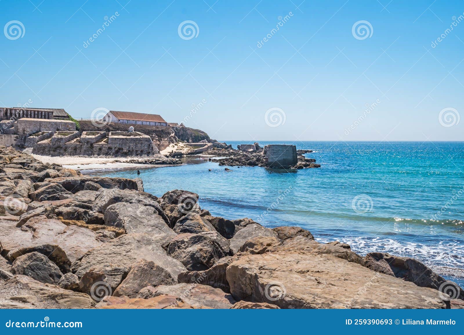 selective focus in rocks with turquoise atlantic ocean and walls of the fort of the island of las palomas next to el foso, tarifa