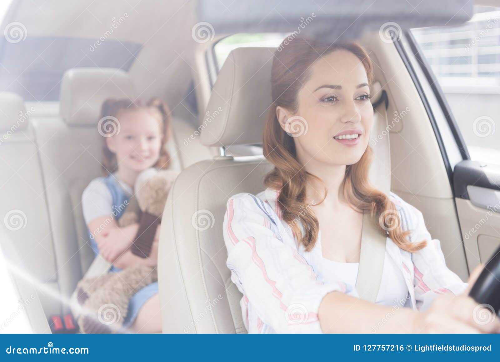 Selective Focus Of Smiling Mother Driving Car With Daughter On