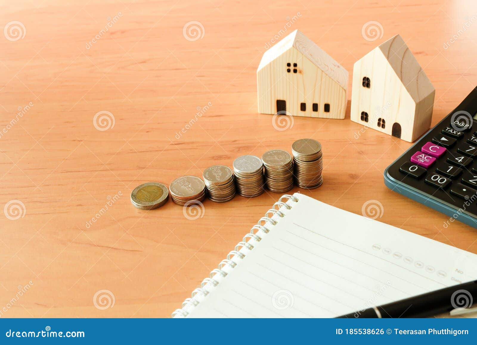 selectove focus of stack of money coin for saving for home, property with small wood house and calculator on the background.