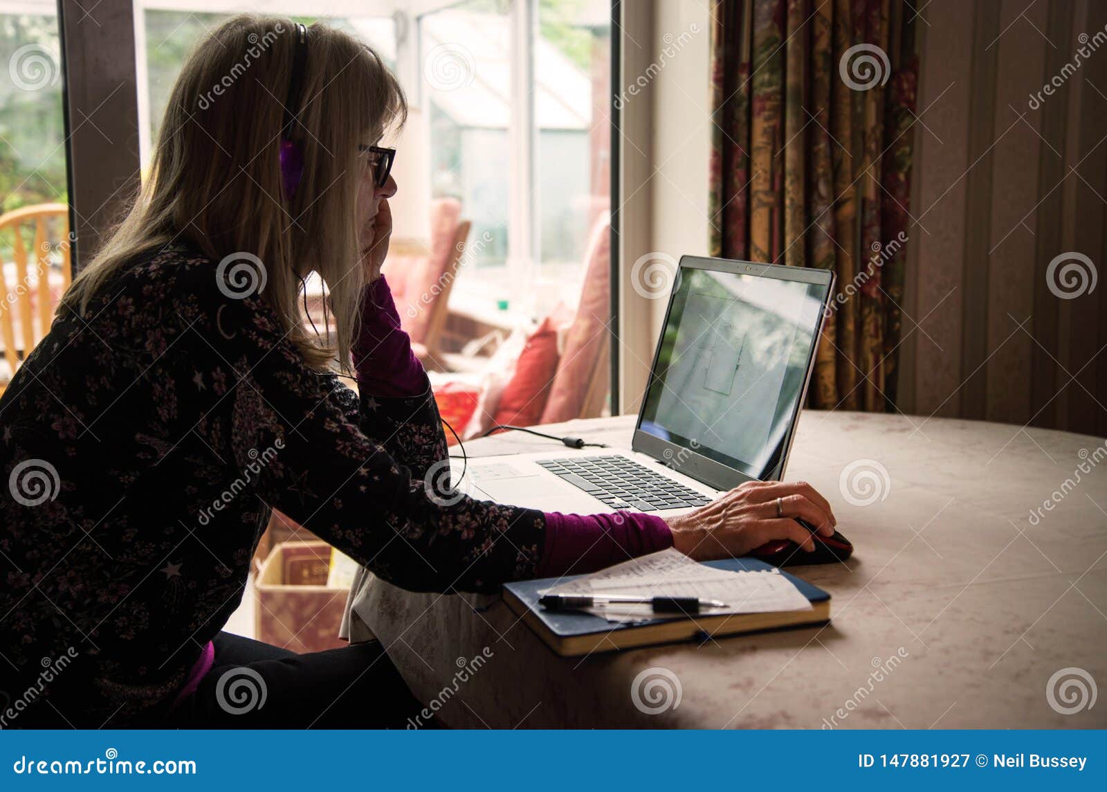 self employed woman listening to webinar on her laptop,wearing headphones