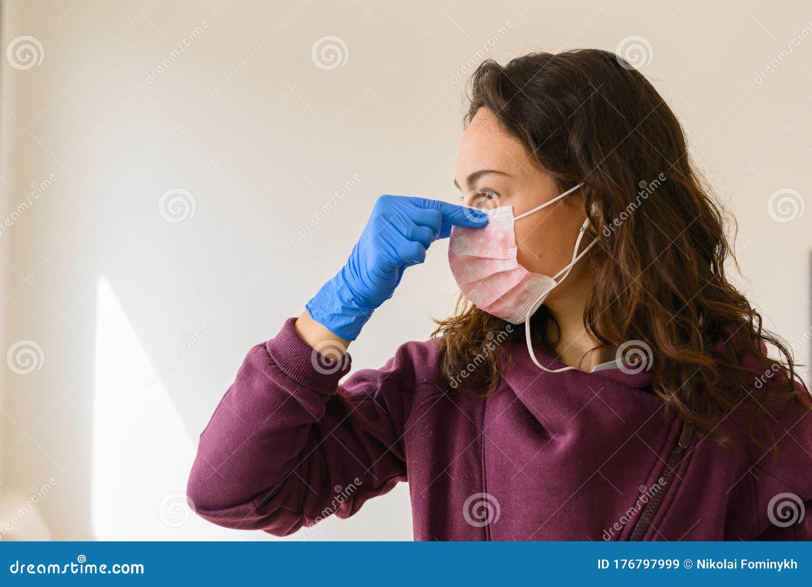 A Young Girl In Blue Gloves Holds A Protective Medical Mask In Her