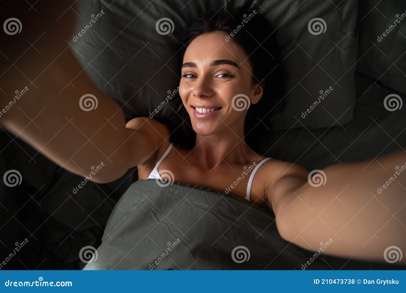 Self Portrait of Woman Lying in Bed Shooting Selfie on Front Camera Enjoying Recreation Biting Finger Having Online Meeting with Stock Photo