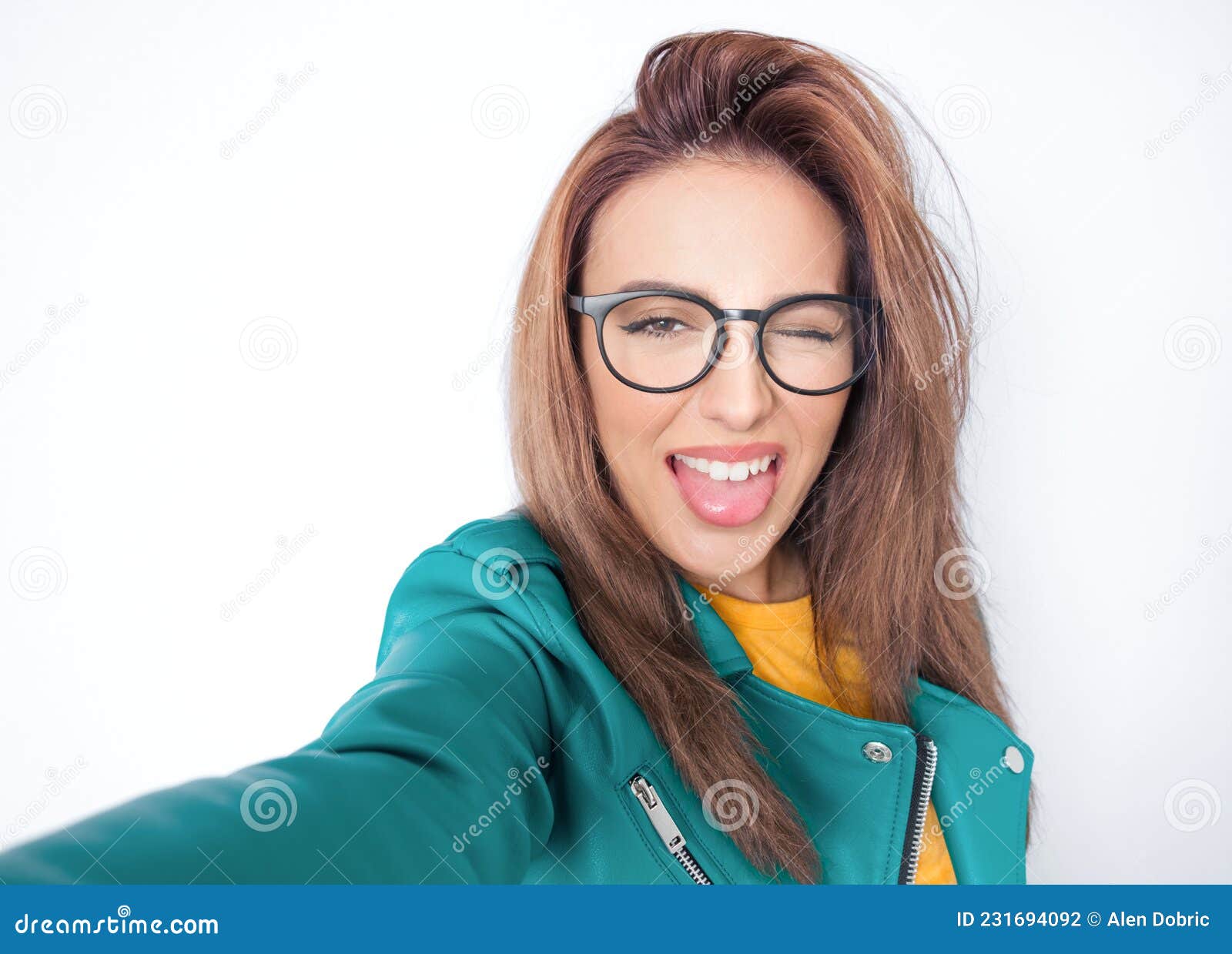 selfie. close-up funny mocked woman takes photo of himself with her smartphone while tongue sticking out, wearing green leather