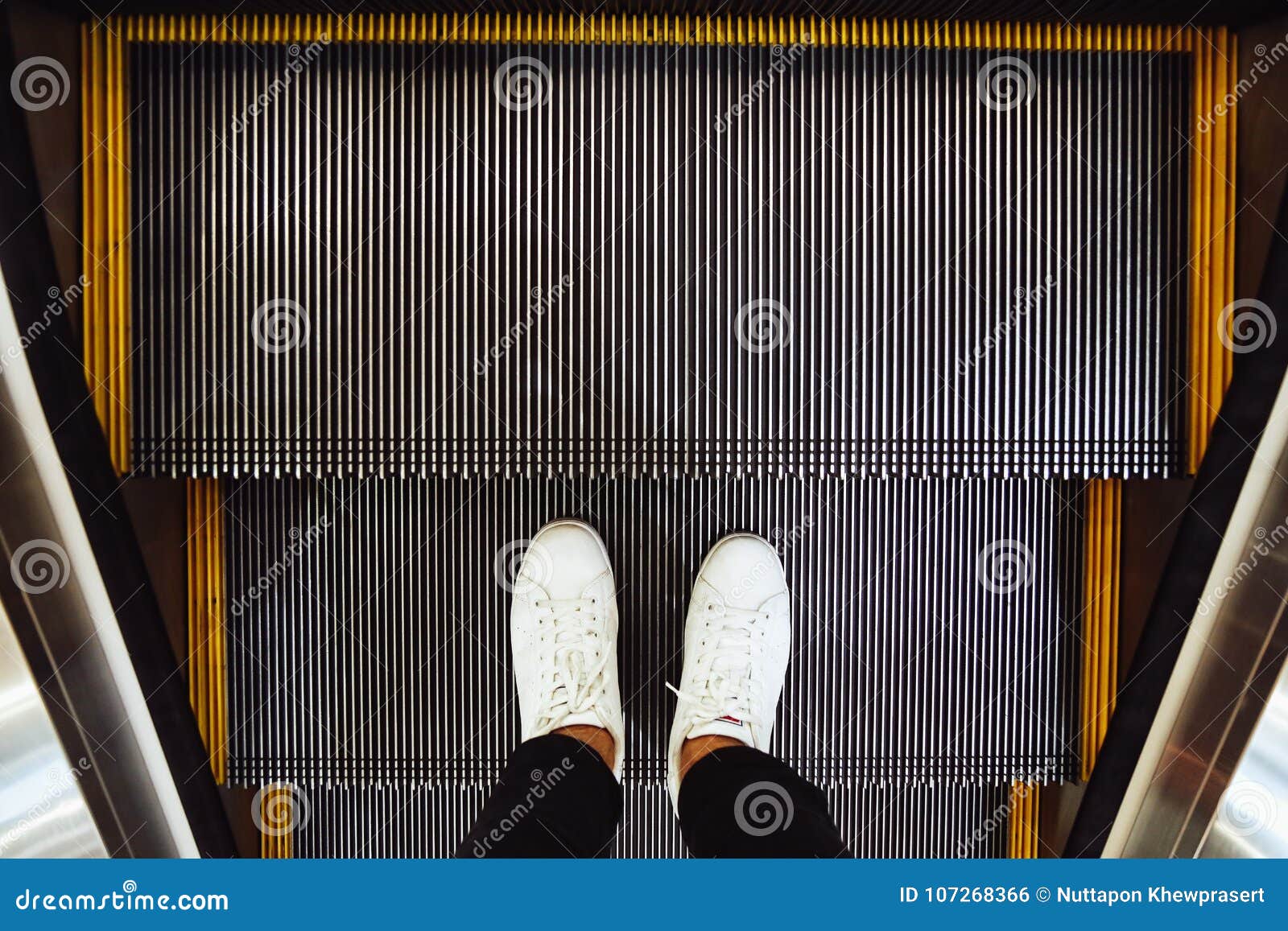 Selfie van mensenvoeten in witte tennisschoenschoenen op roltrapstappen in het winkelcomplex, hoogste mening in uitstekende stijl