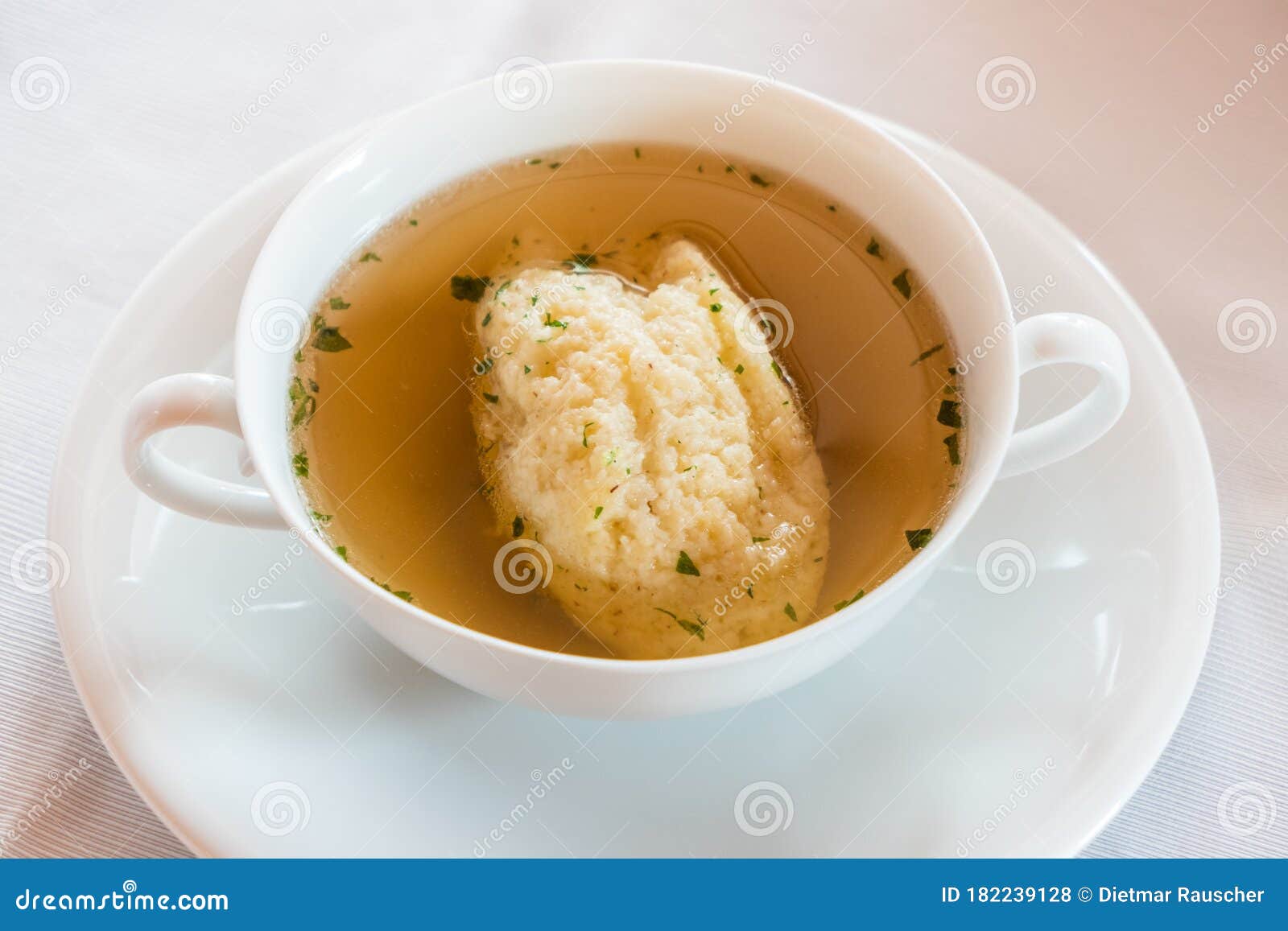 semolina dumpling soup, beef broth in a white bouillon cup