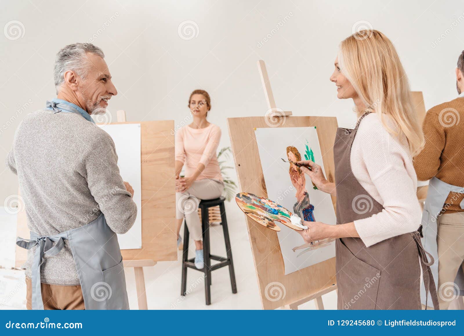 senior artists painting and looking at each other
