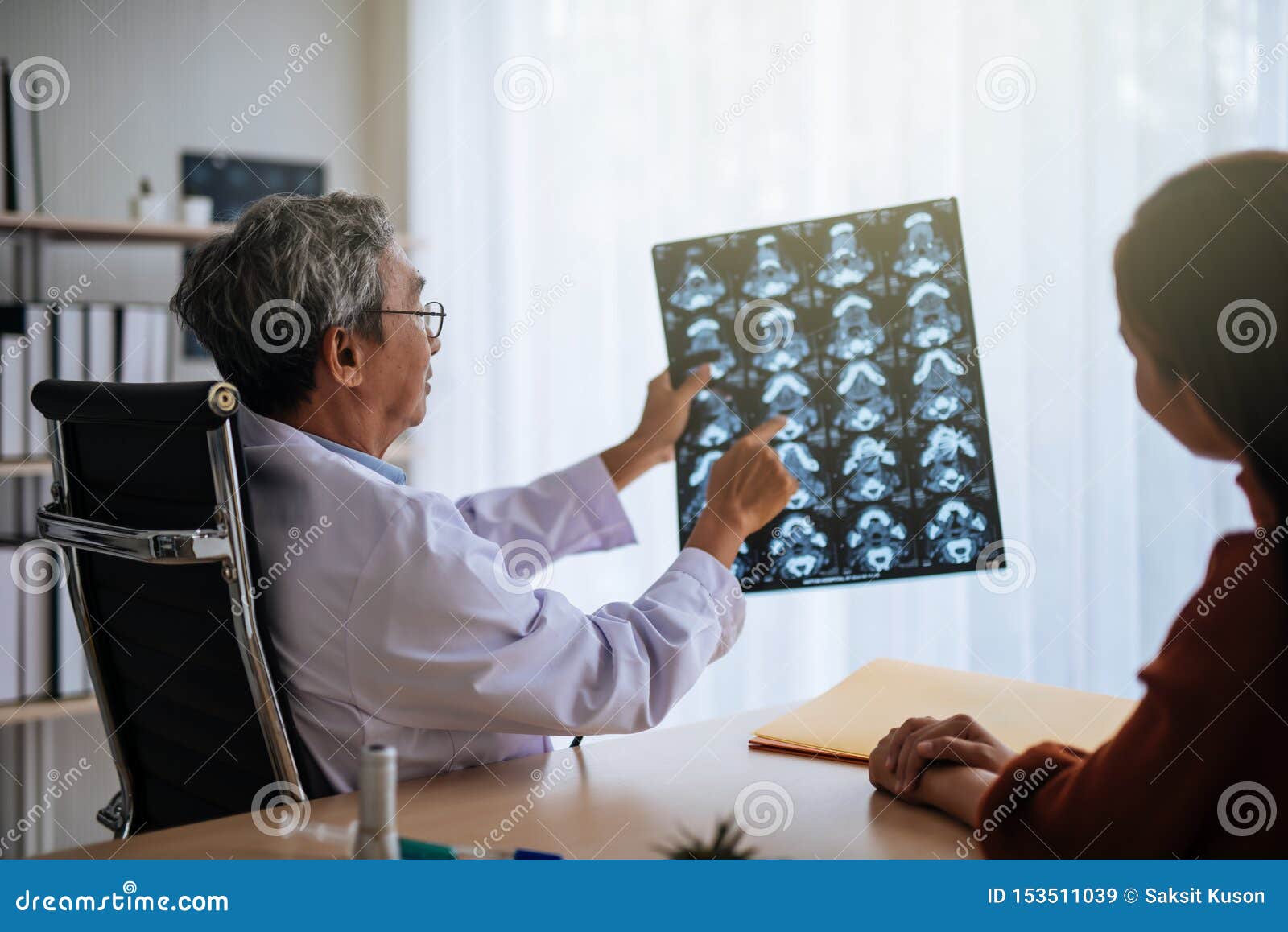 senior asian doctor examine mri picture explain to patient.