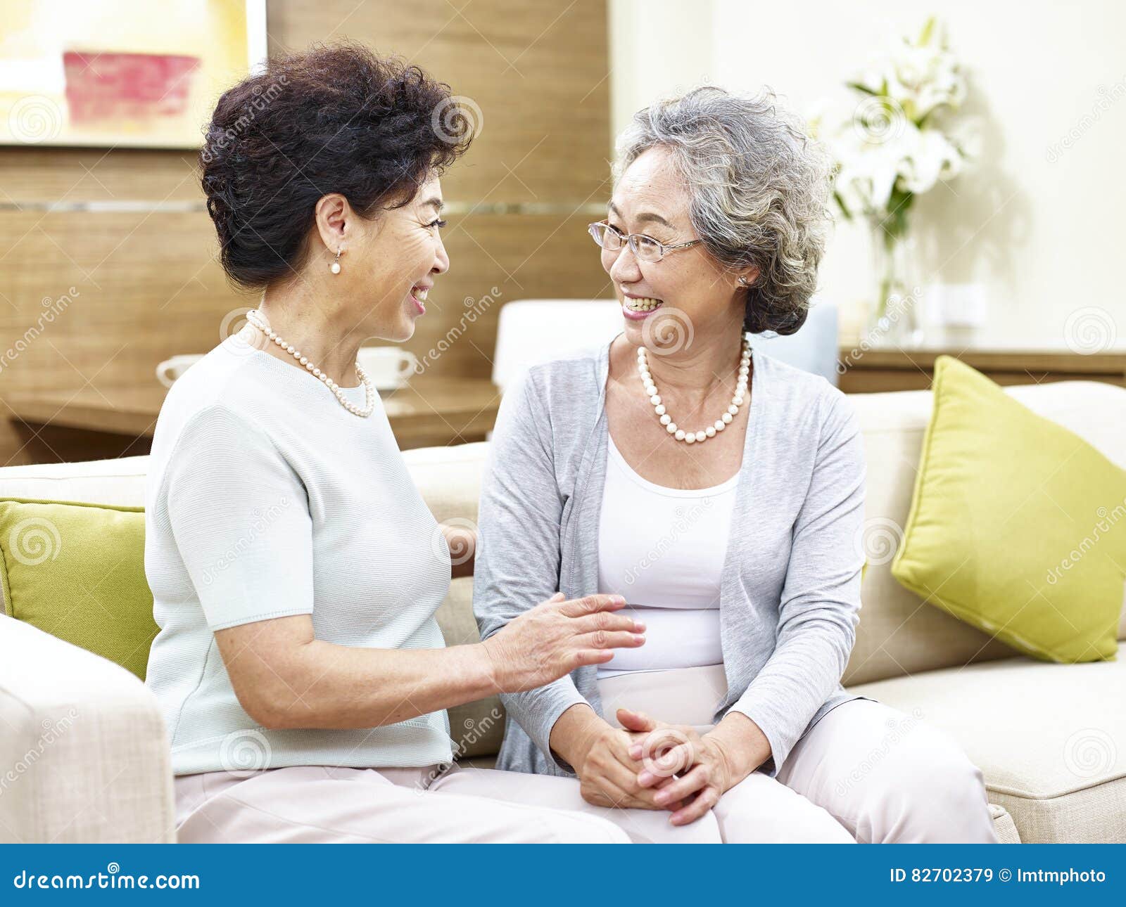 senior-asian-woman-chatting-home-two-women-sitting-sofa-happy-smiling-82702379.jpg