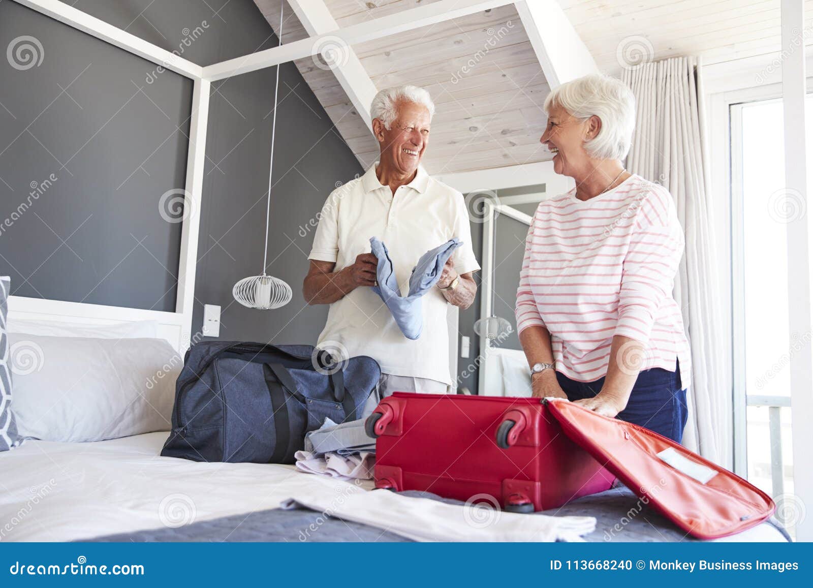 senior couple in bedroom packing suitcase for vacation