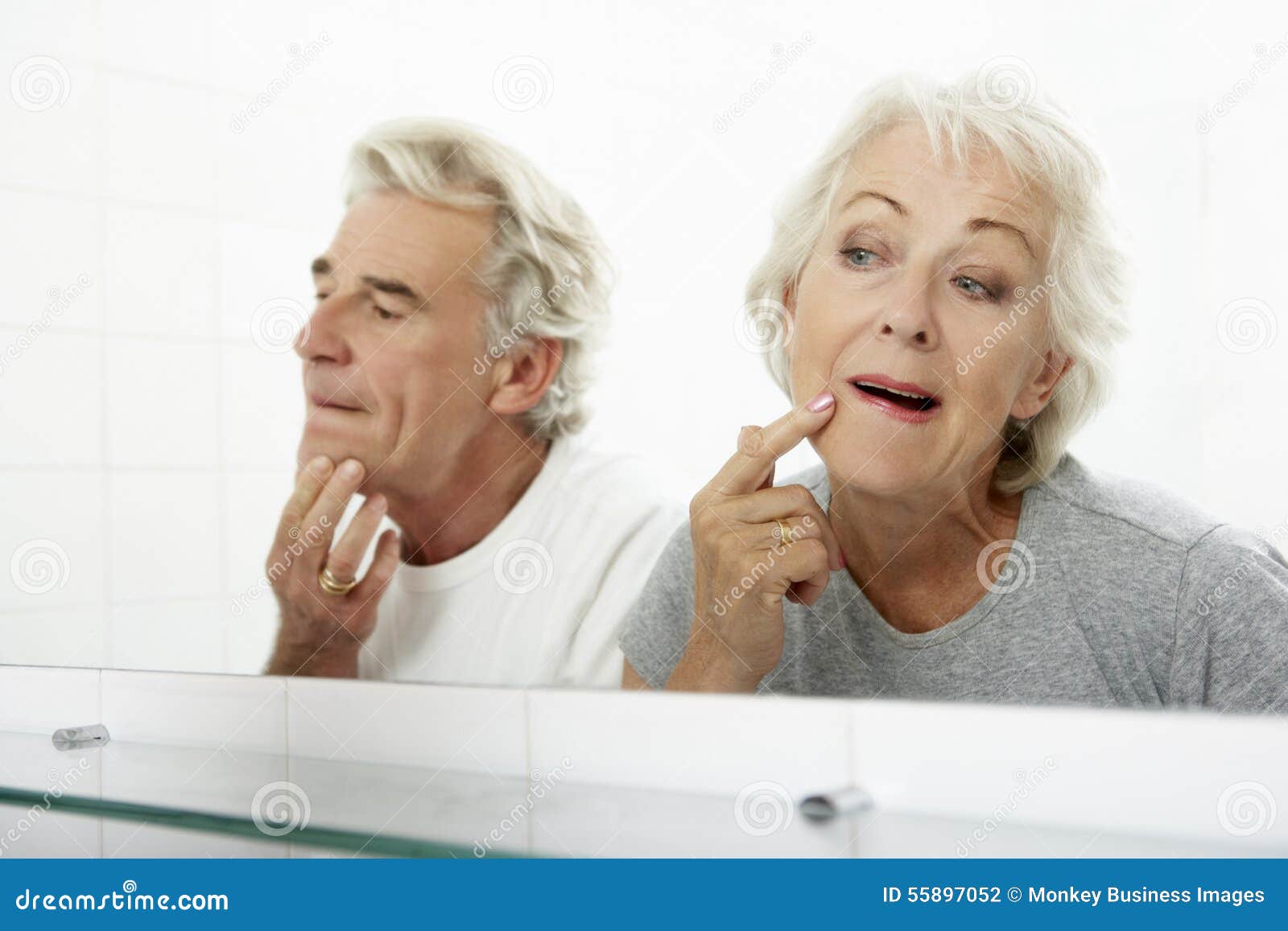 Senior Couple Looking at Reflections in Mirror for Signs of Ageing