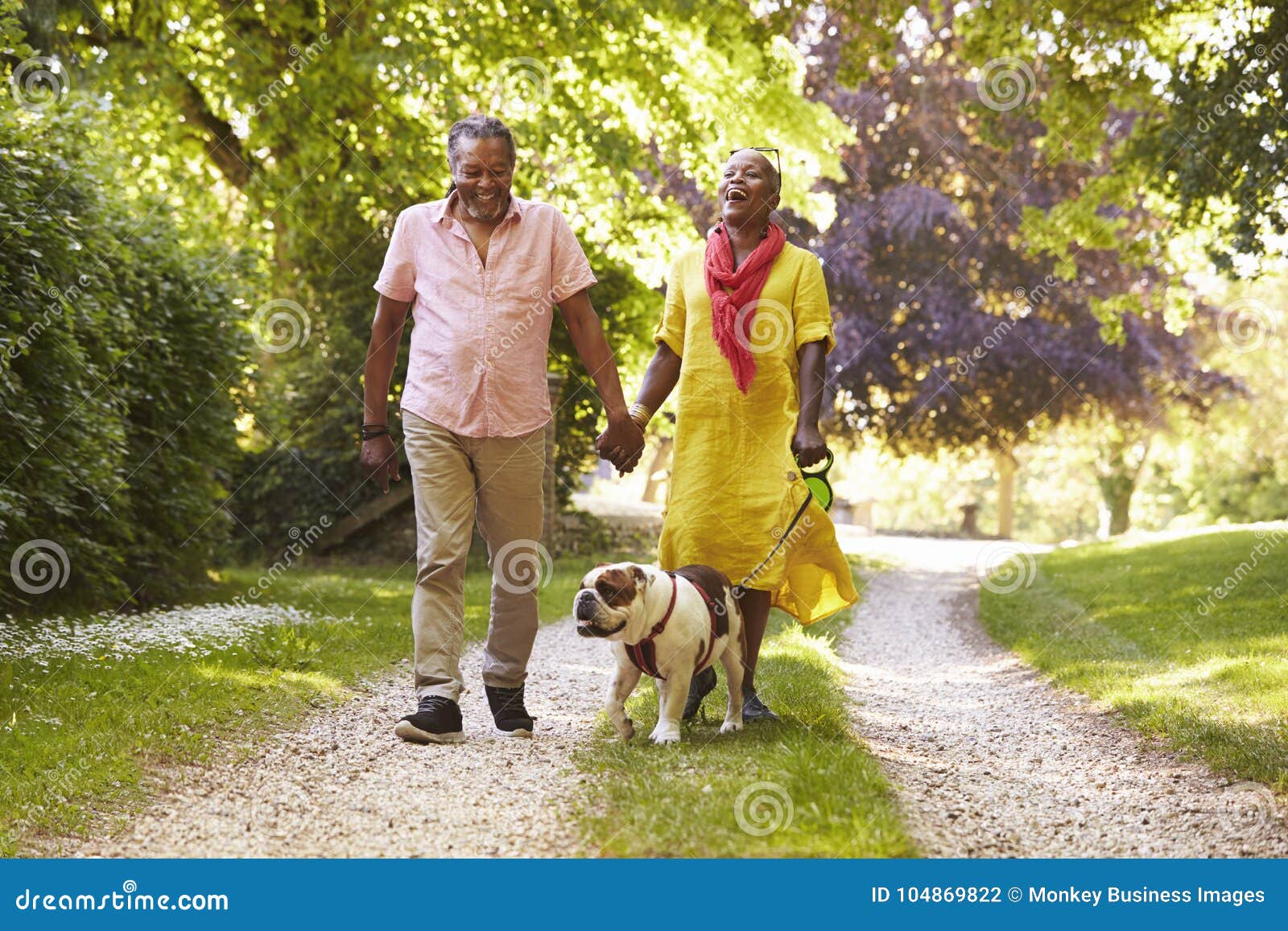 senior couple walking with pet bulldog in countryside