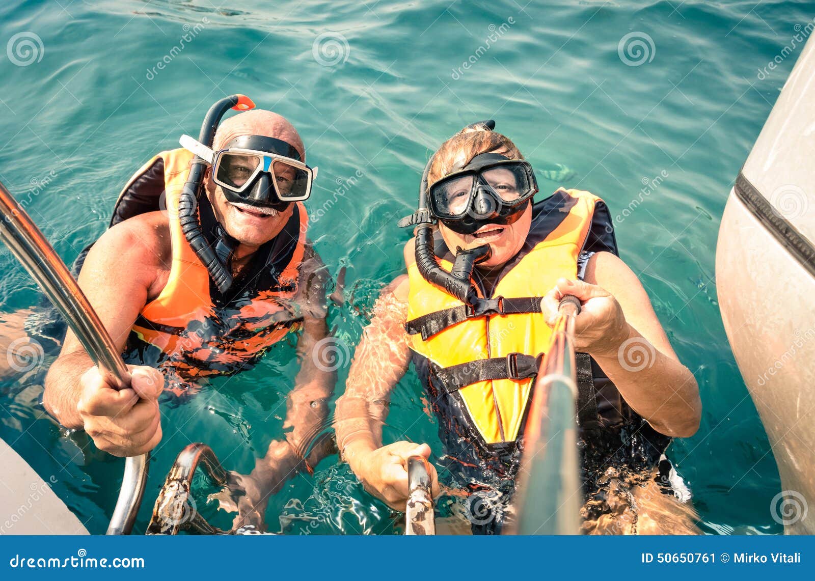 senior happy couple using selfie stick in tropical sea excursion