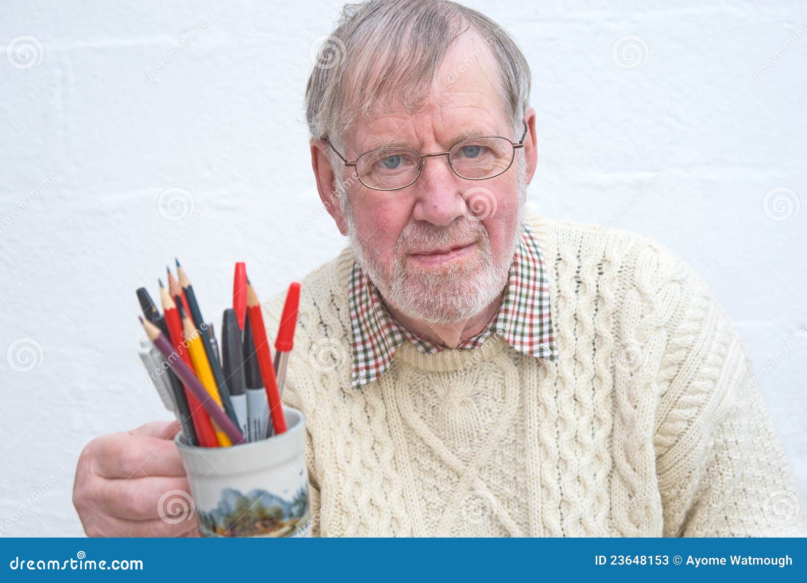 senior holding a mug of pens and pencils.