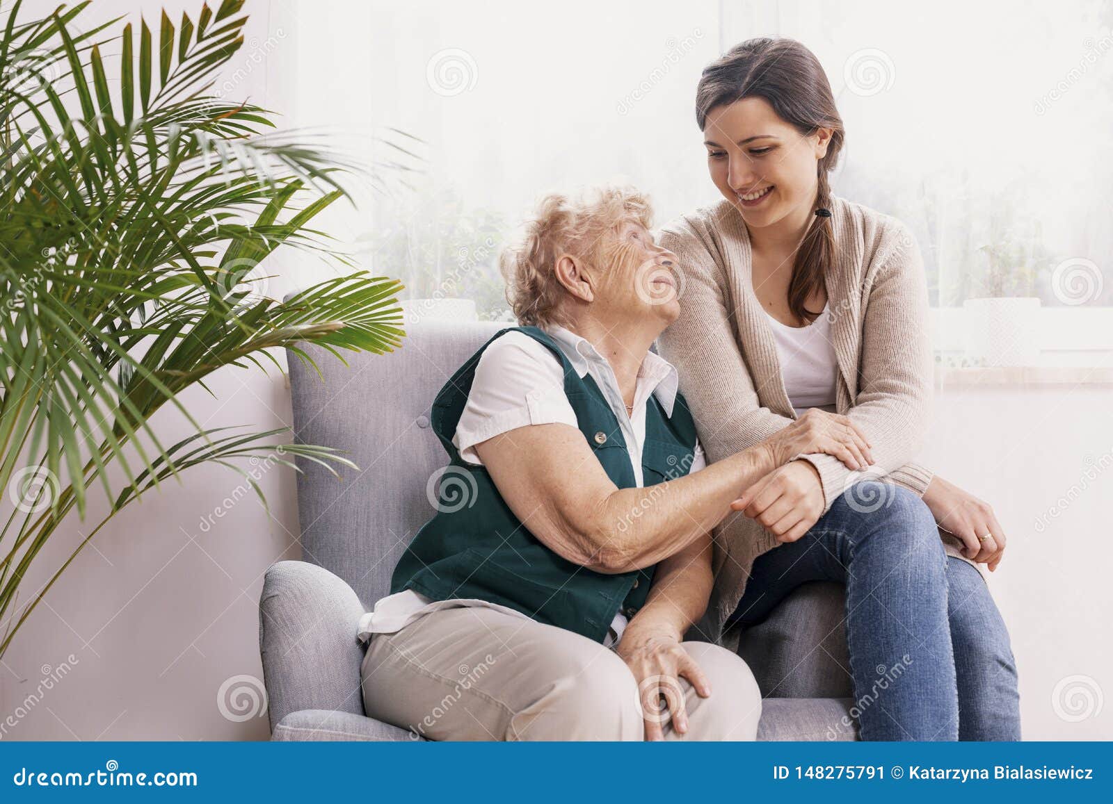 senior lady sitting in armchair at nursing home, supporting nurse