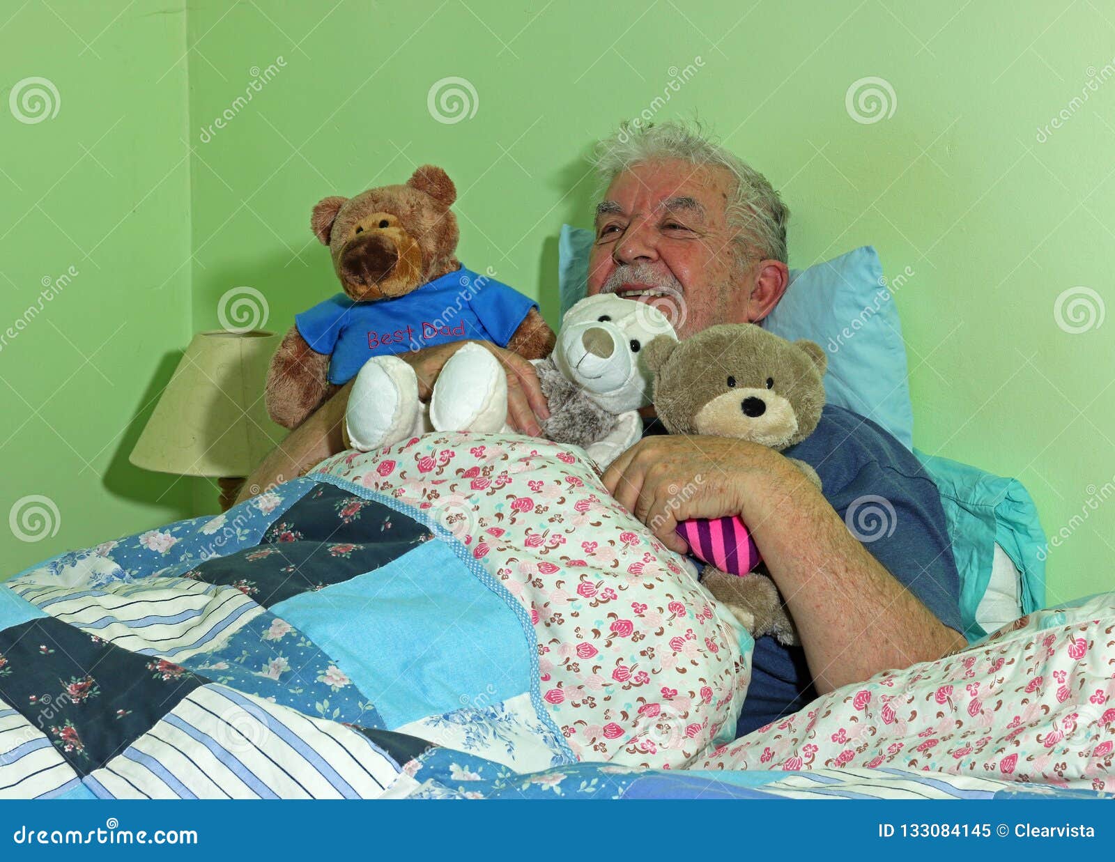 senior man in bed with soft cuddly toys.