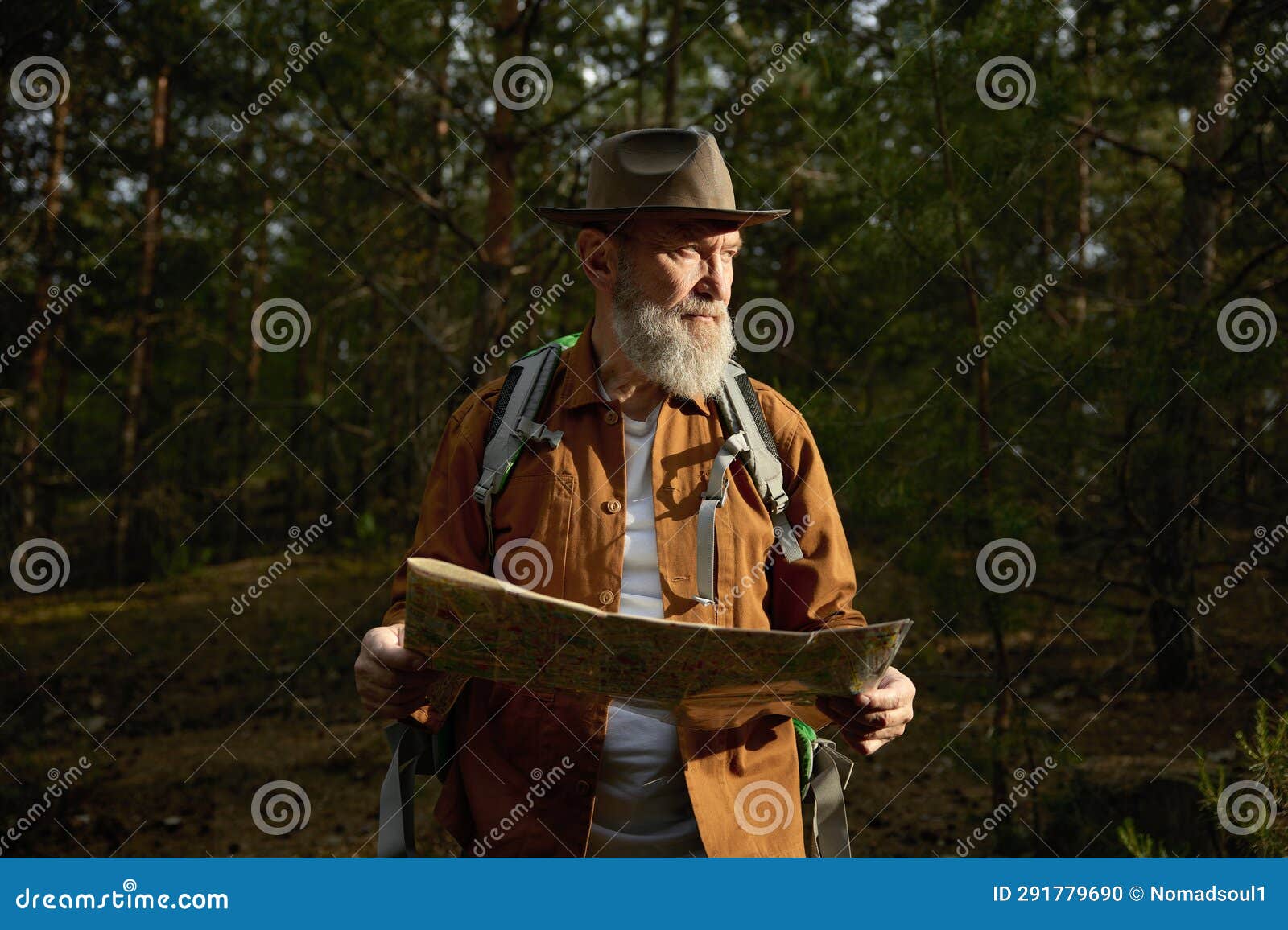 senior man hiker looking in paper map searching rout in forest