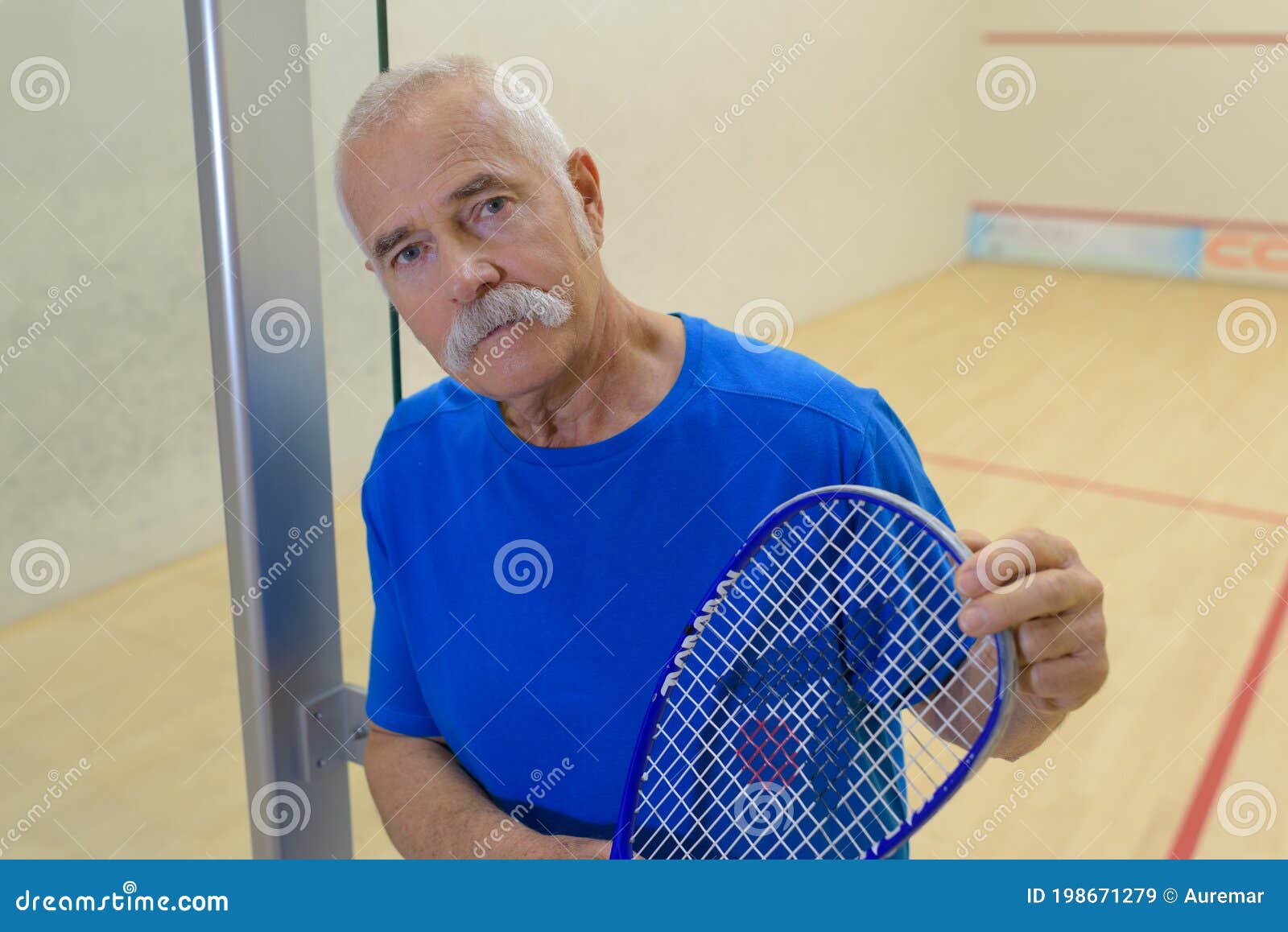senior man on indoor court holding raquet
