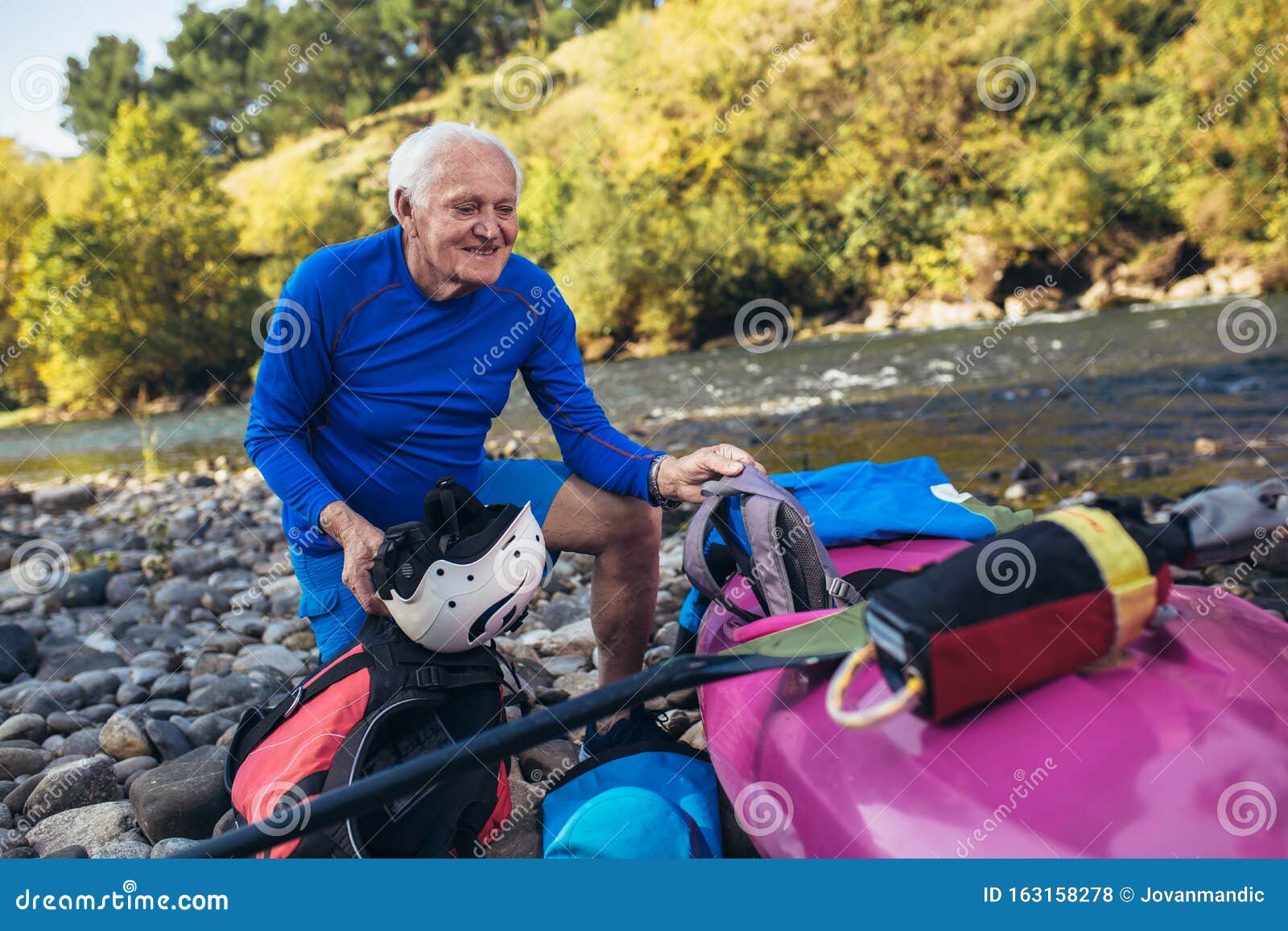 Senior Man Preparing for Kayak Tour on a Mountain River Stock Photo