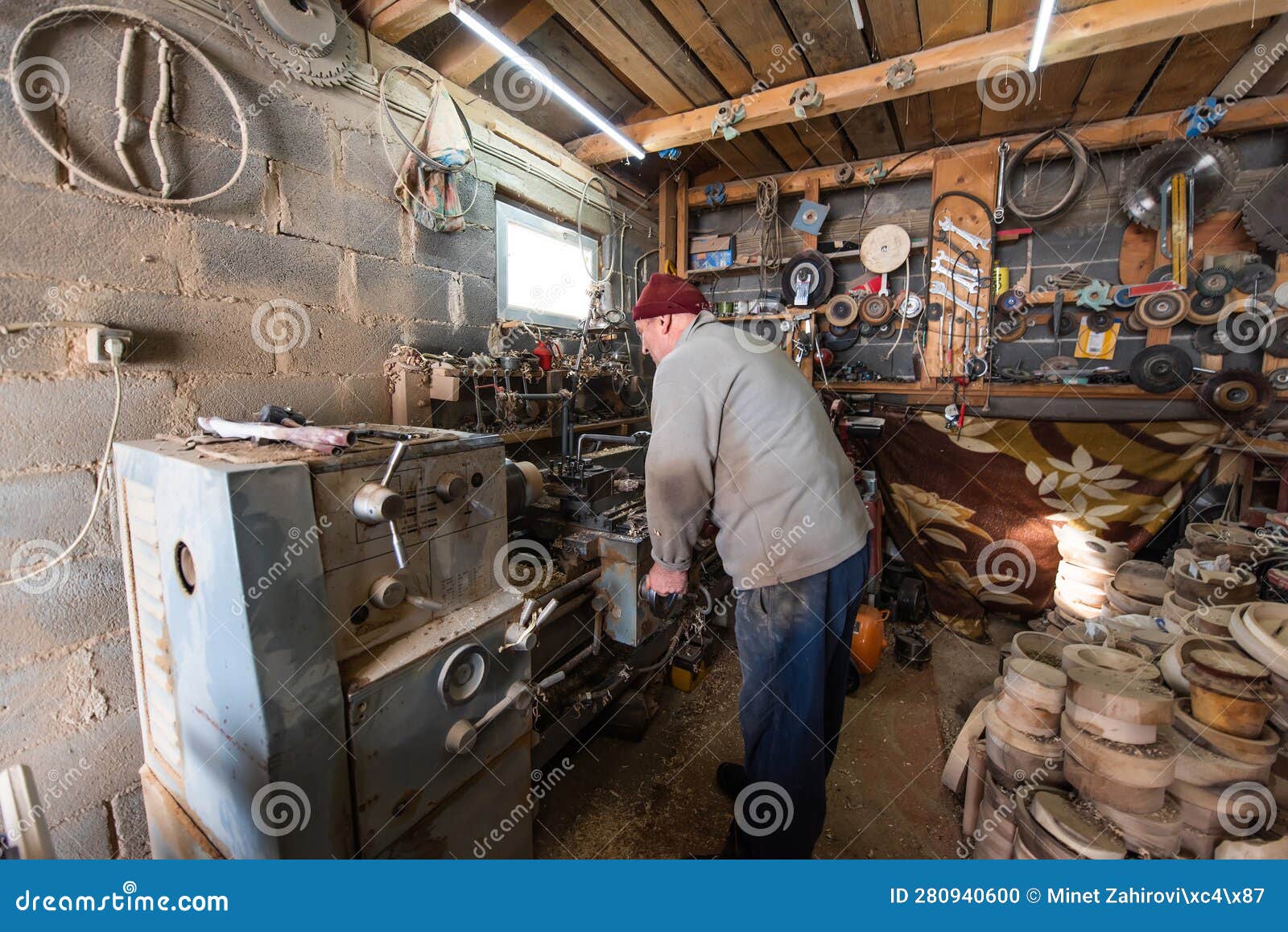 a senior man procesing wood on a lathe and making wooden dishes in the workshop