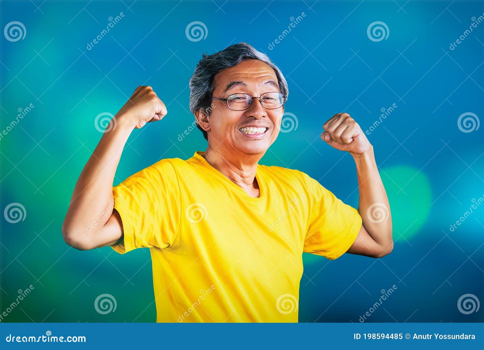 senior man showing off muscle for strong healthy lifestye concept on blue bokeh background