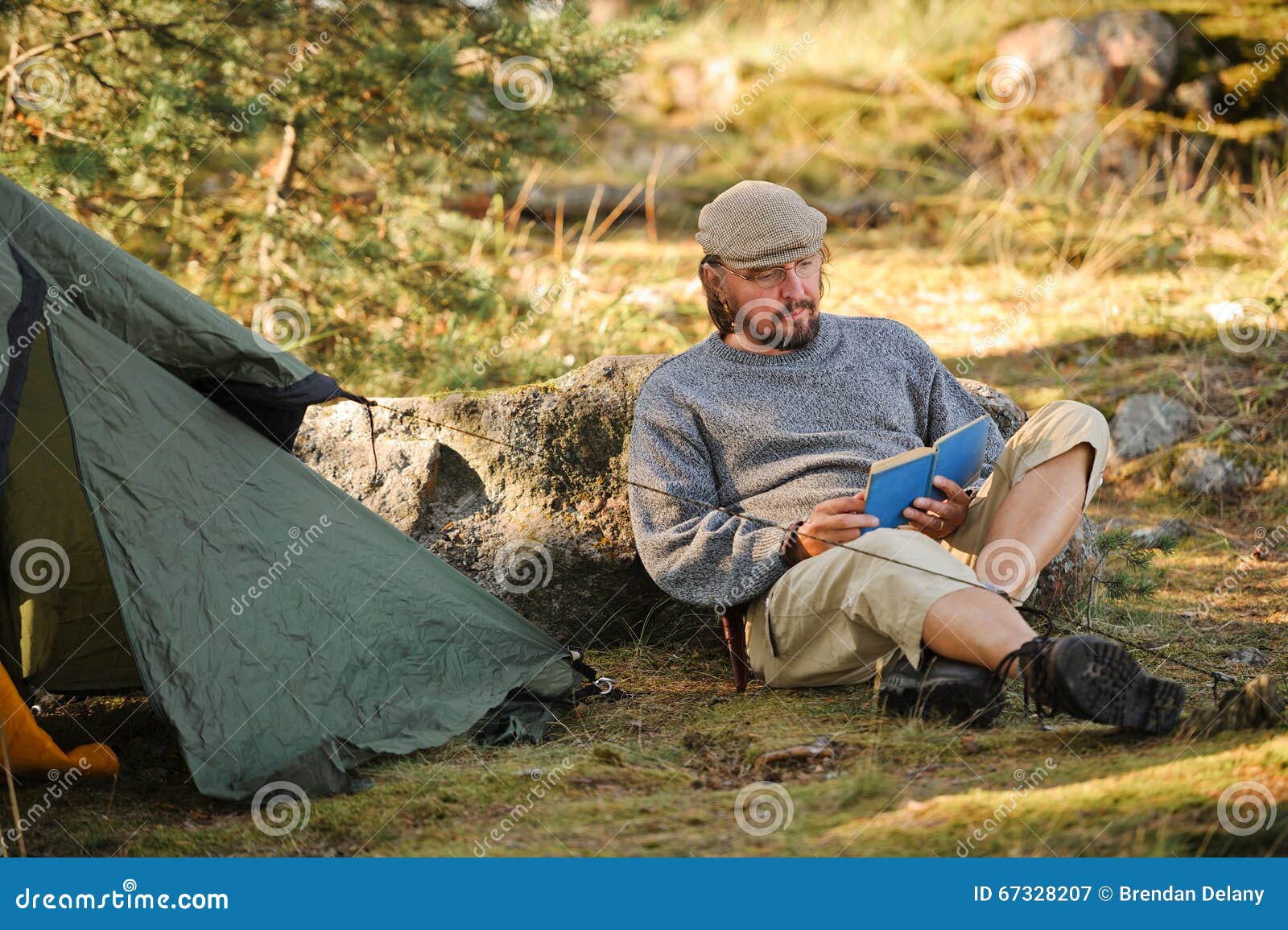 Senior Man Sitting Outside a Tent Reading a Book Stock Image - Image of ...