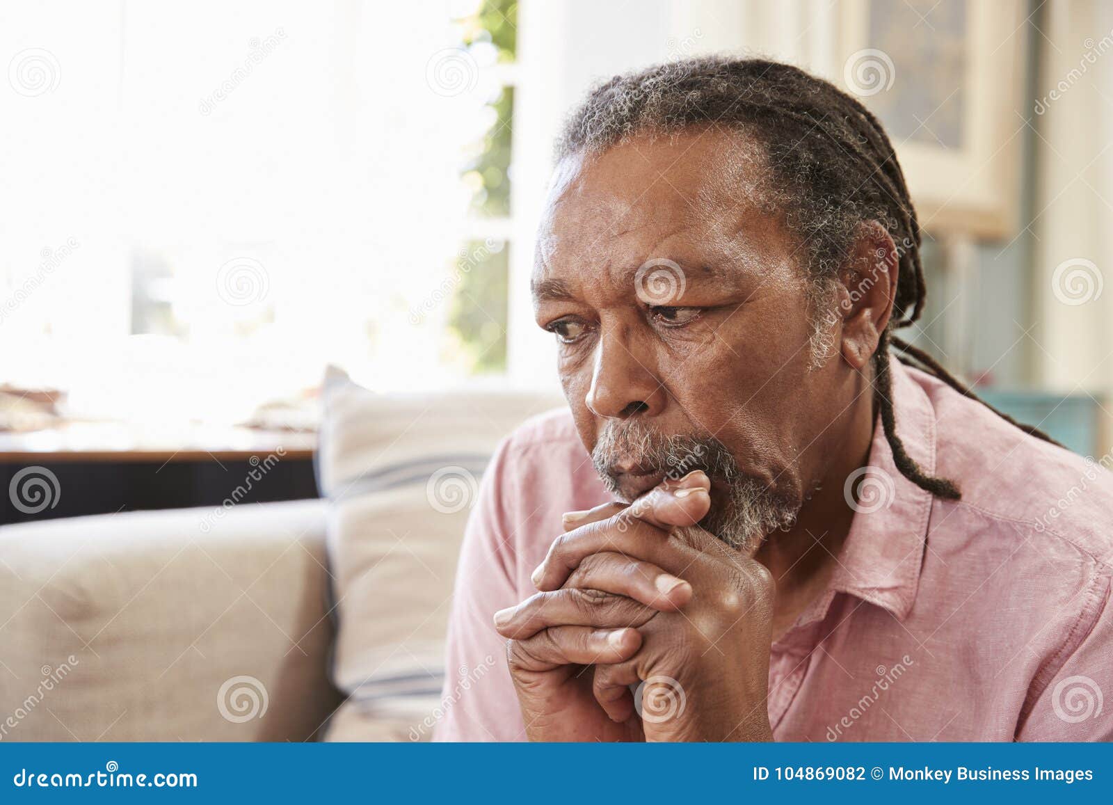 senior man sitting on sofa at home suffering from depression