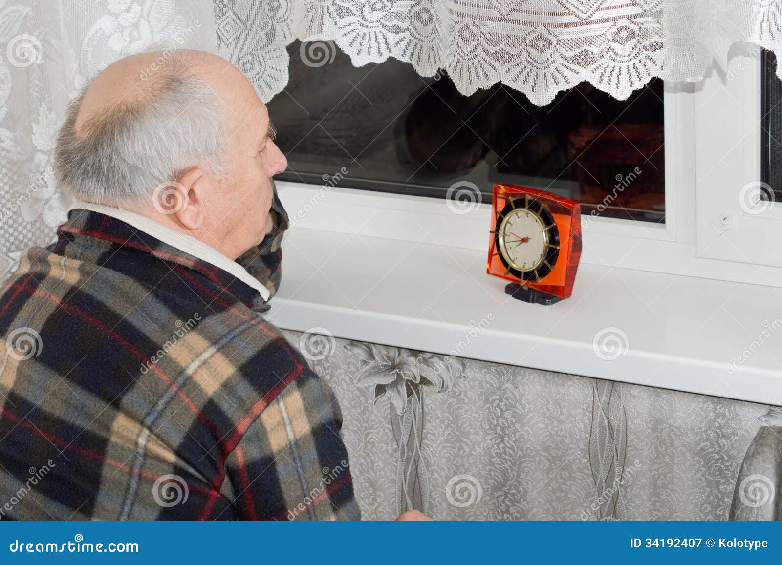 senior man sitting waiting at night with a clock