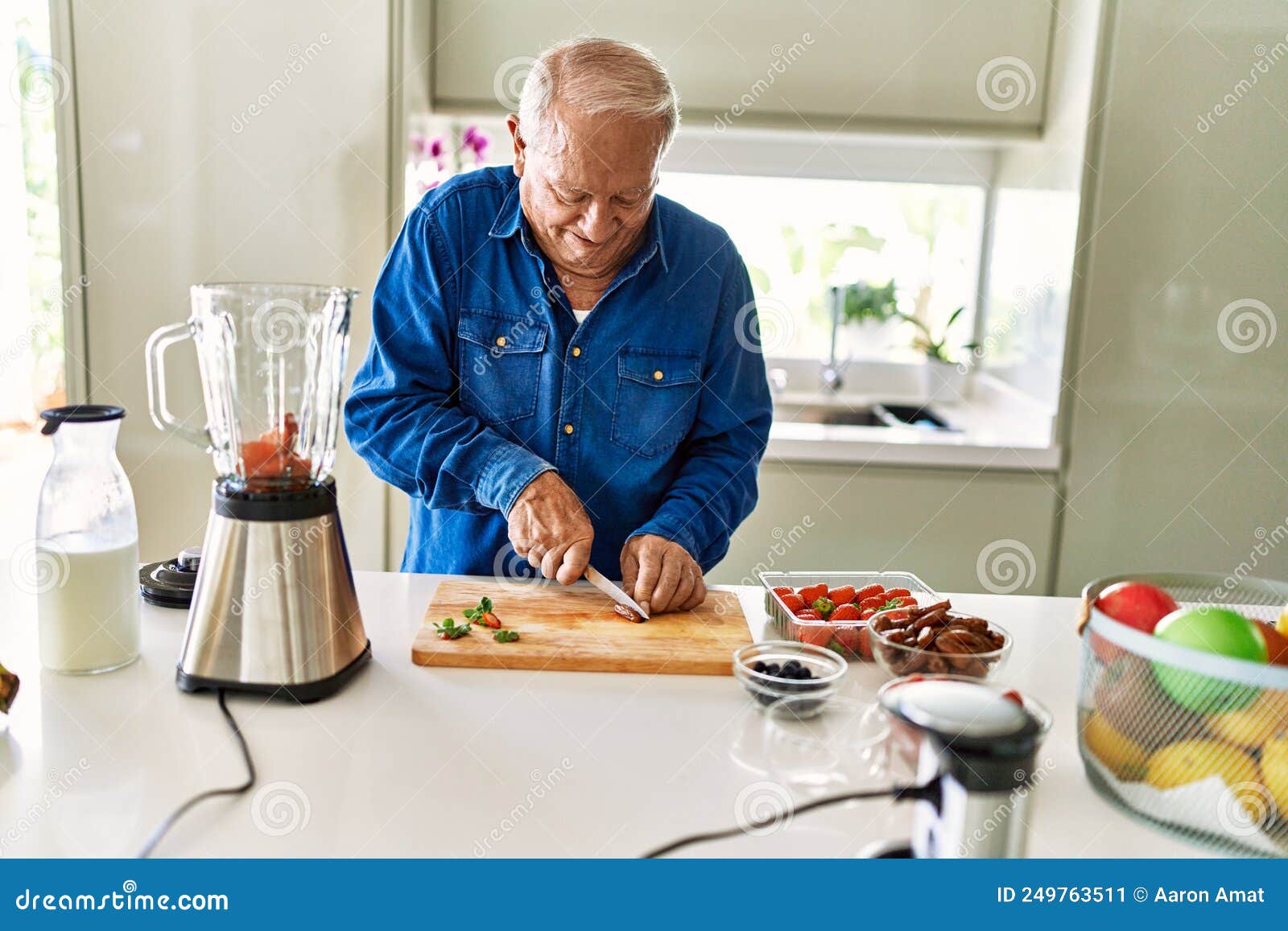 senior man smiling confident cutting datil at kitchen
