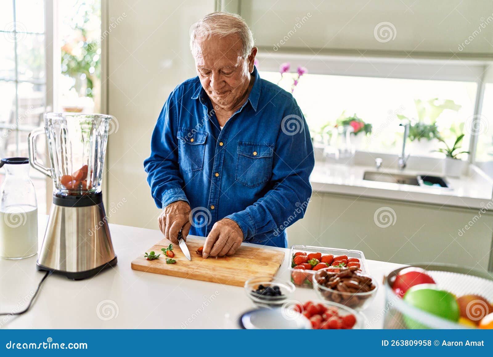 senior man smiling confident cutting datil at kitchen