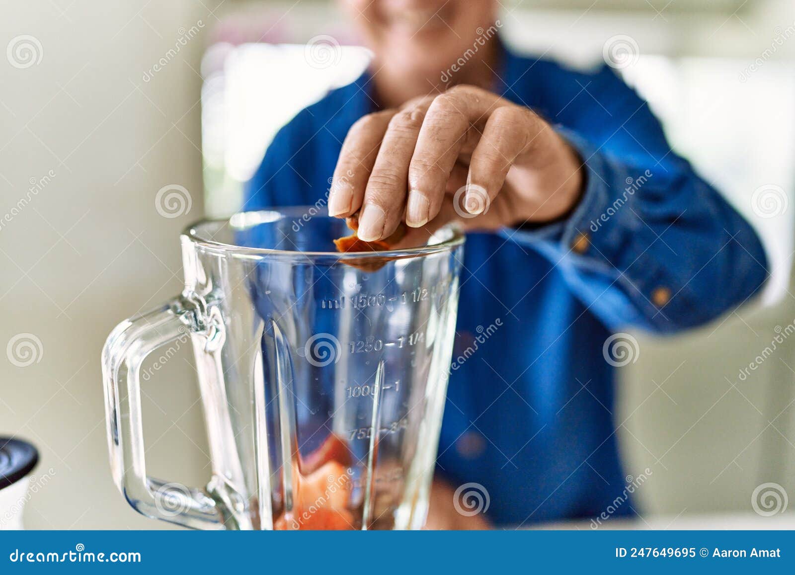 senior man smiling confident putting datil in blender at kitchen