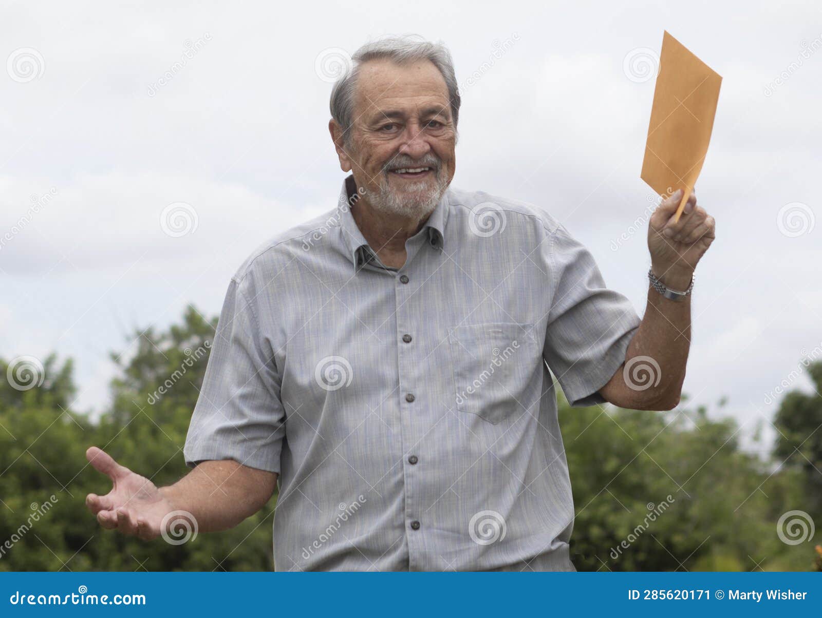 senior man smiling holding manilla envelope