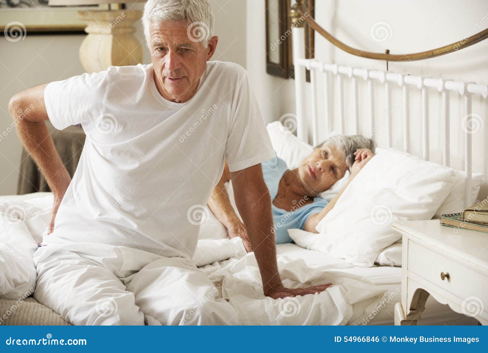 Senior Man Suffering from Backache Getting Out of Bed Stock Photo