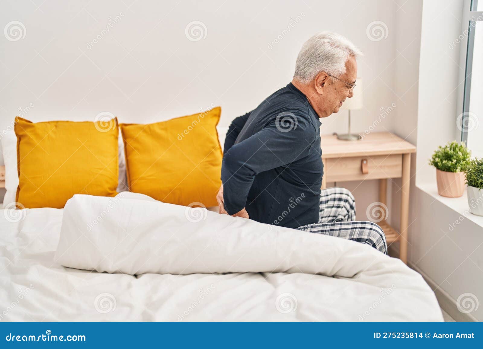 Senior Man Suffering for Backache Sitting on Bed at Bedroom Stock Photo