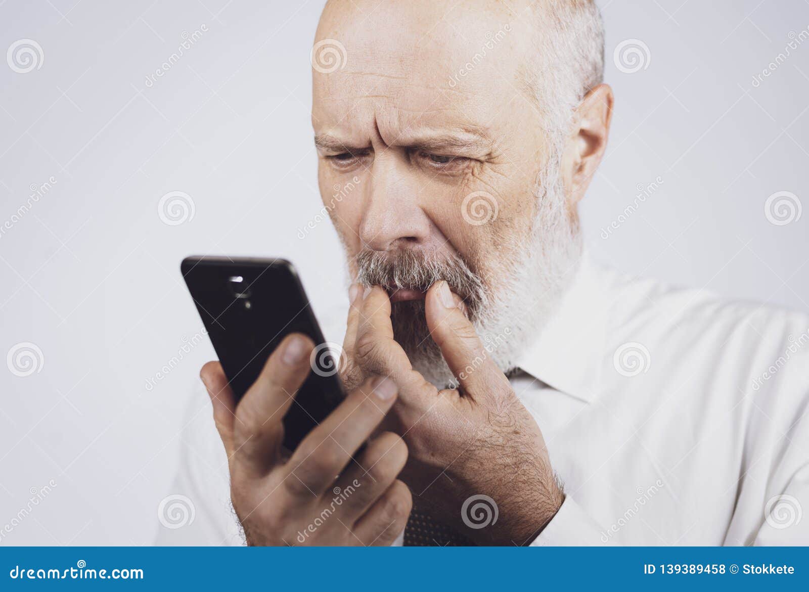 Senior Man Using a Phone and Having Eyesight Problems Stock Photo