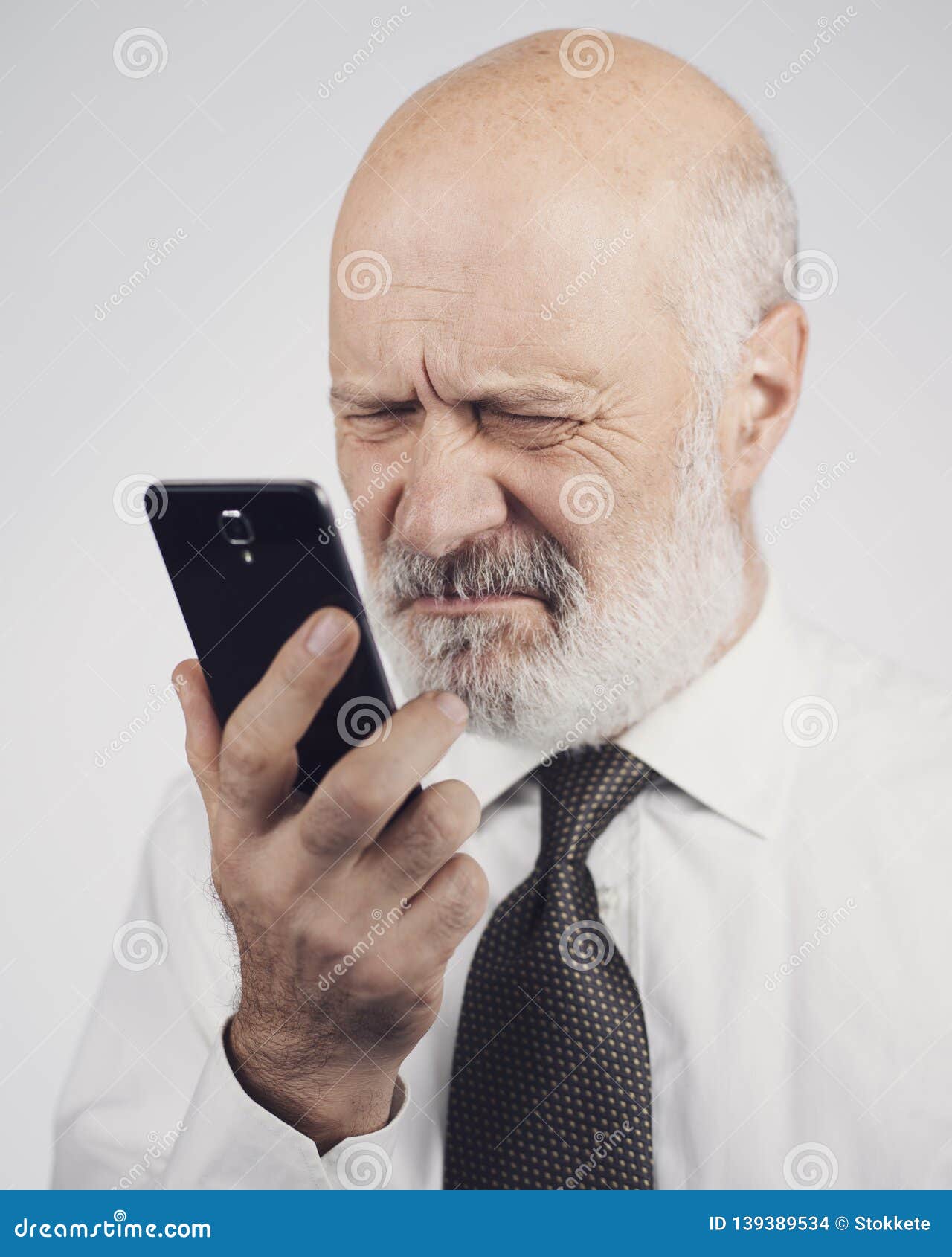 Senior Man Using a Phone and Having Eyesight Problems Stock Photo