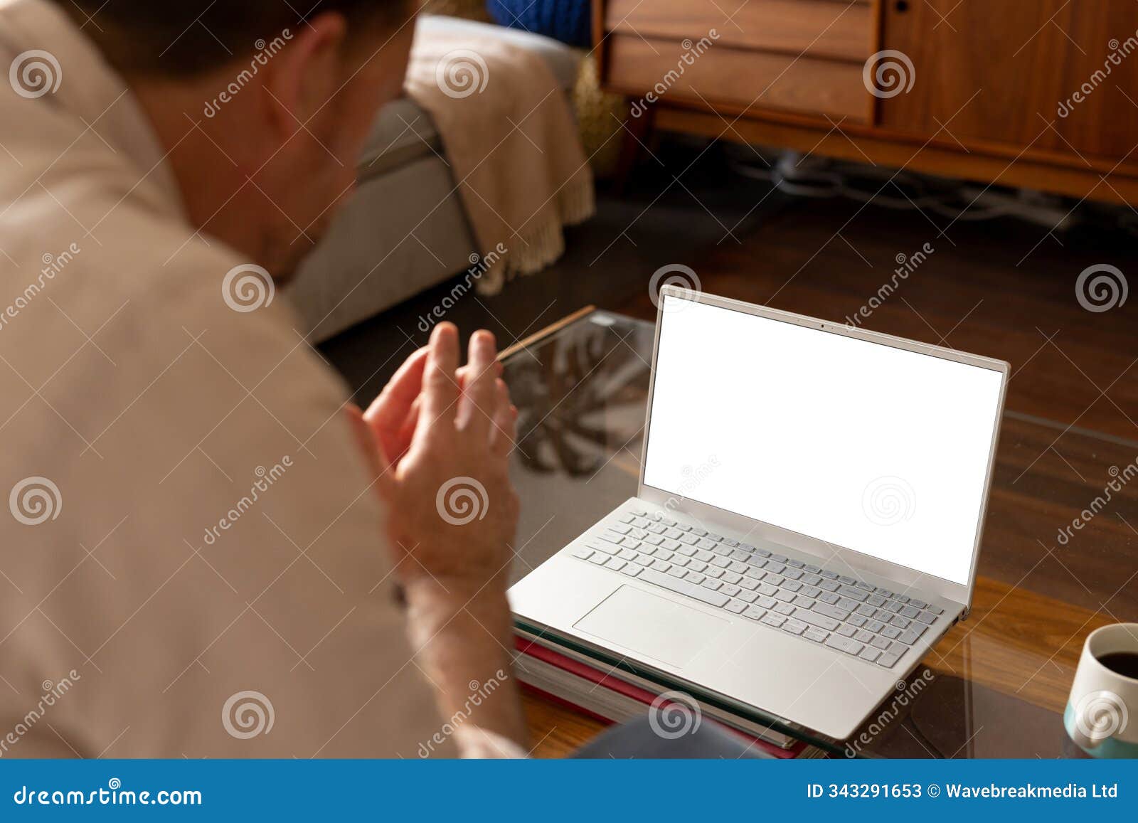 senior man video conferencing on laptop at home, engaging in virtual meeting, copy space