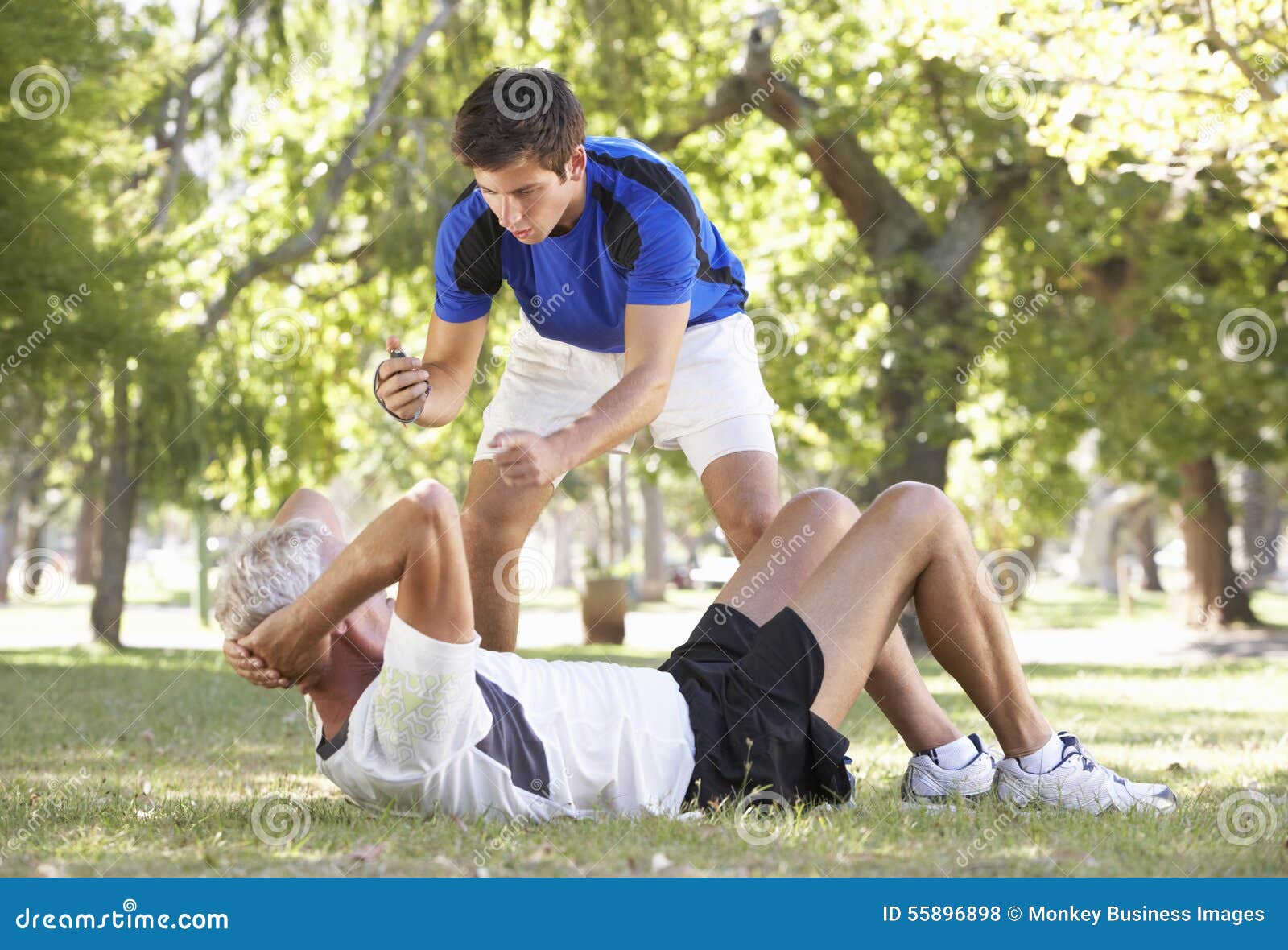 Senior Man Working With Personal Trainer In Park Stock