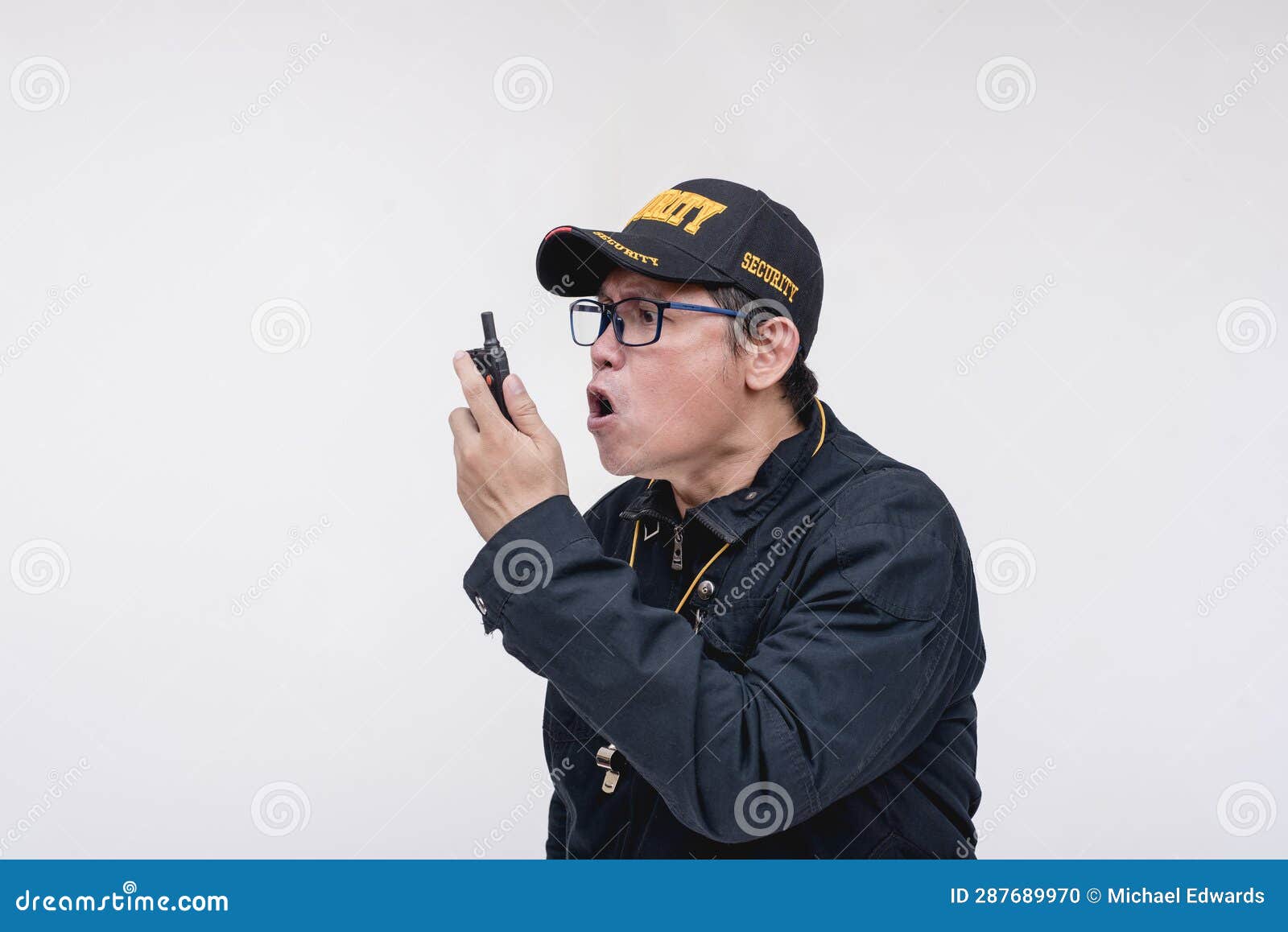 a senior security guard barks orders on his walkie-talkie or handheld transceiver. a strict superior giving commands.  on