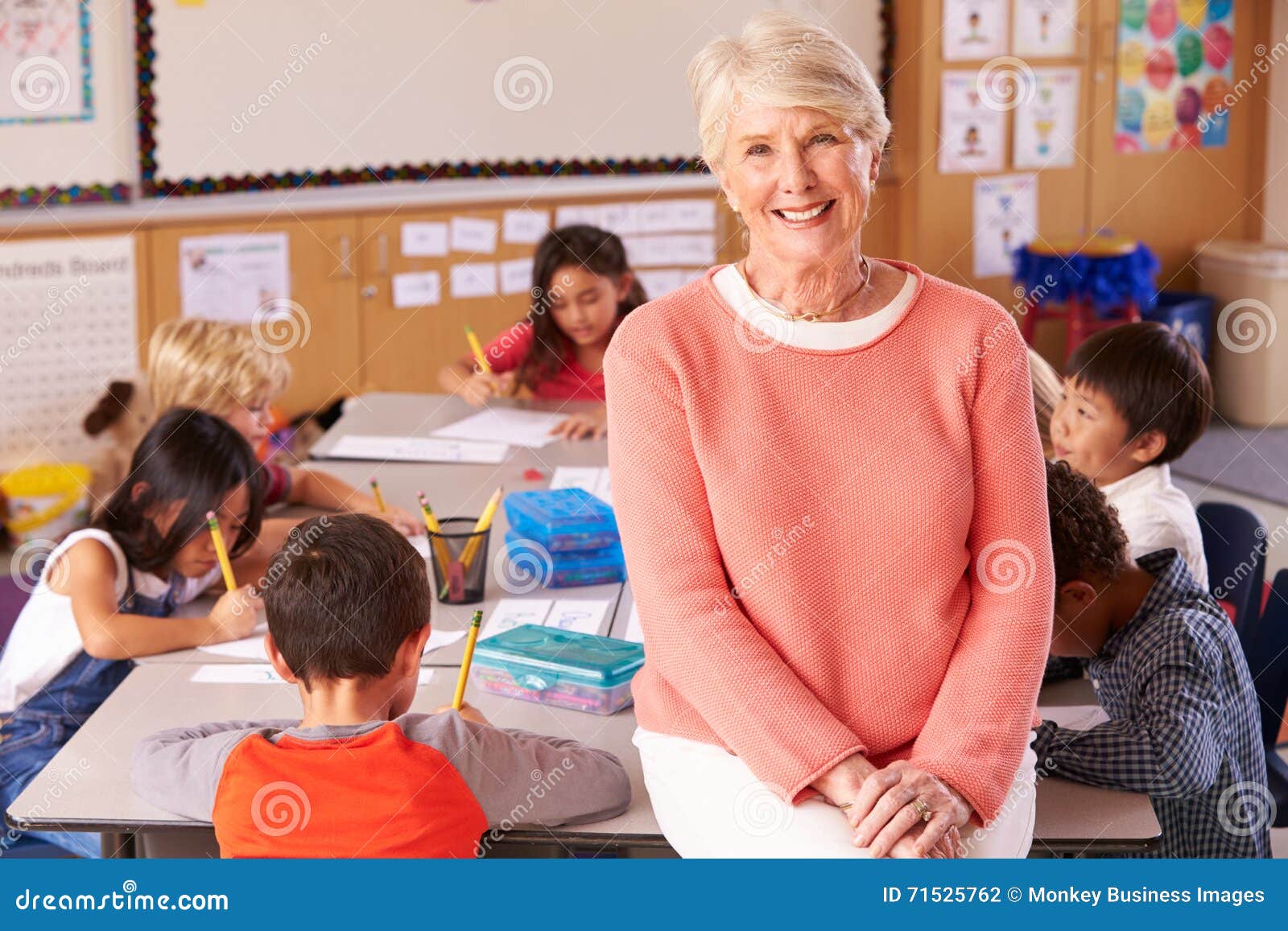 senior teacher in classroom with ary school kids