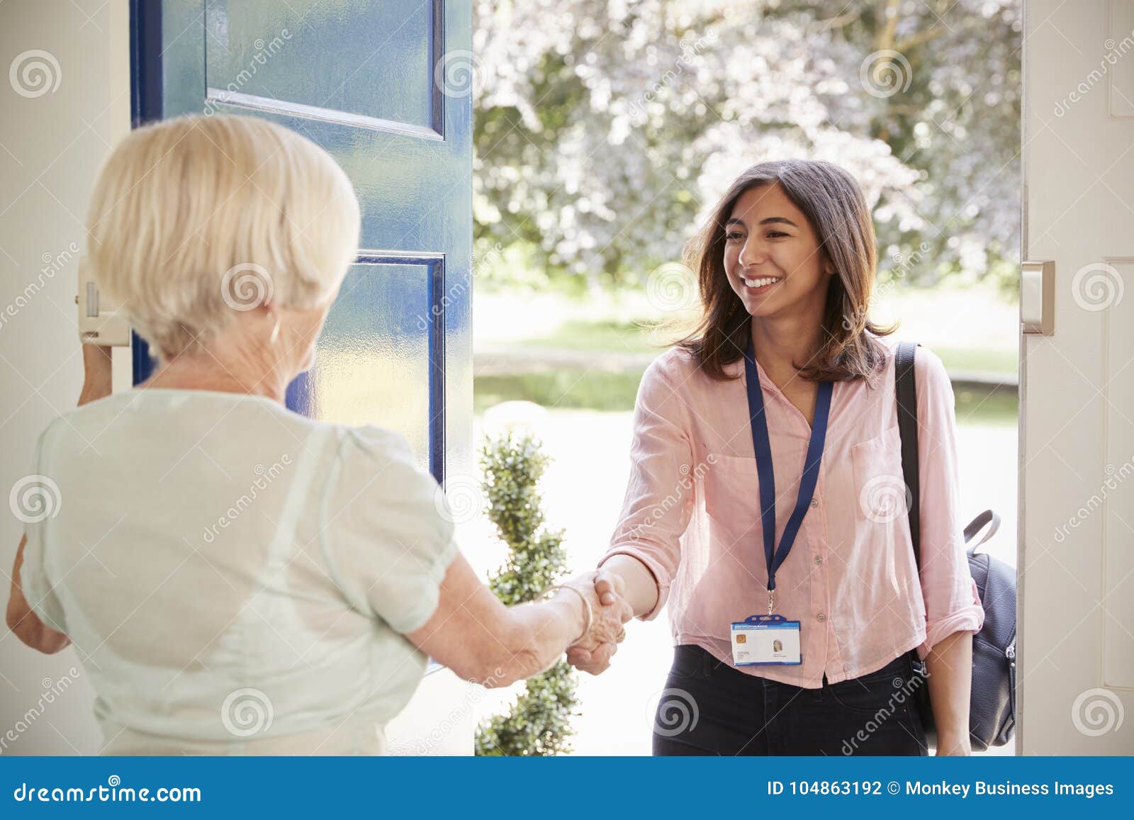 senior woman greeting female care worker making home visit